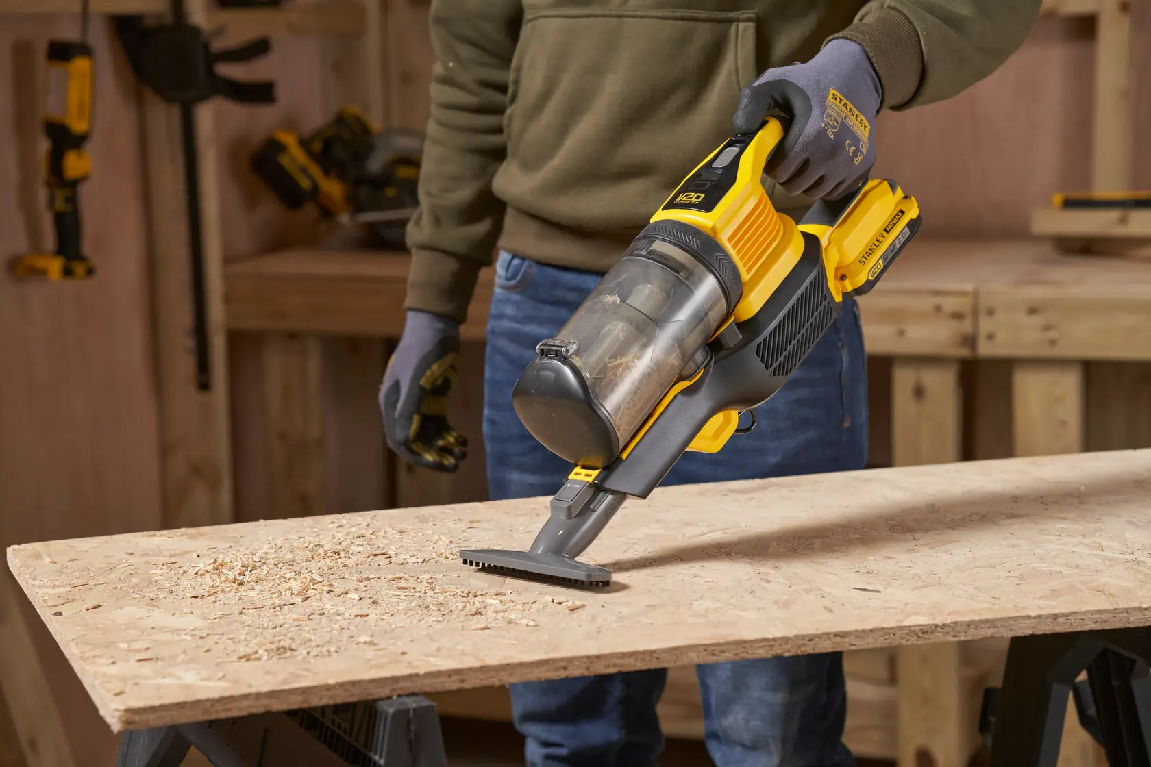 STANLEY SFMCVS001D1 aspirapolvere portatile in uso per pulire trucioli di legno su un banco da lavoro, vista laterale.