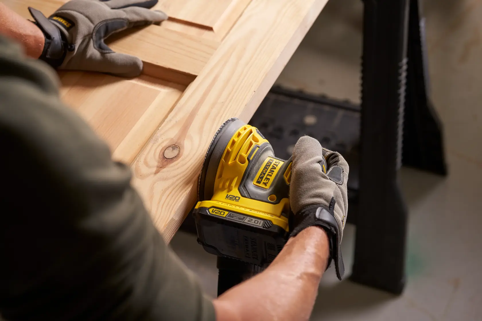 Photo de la ponceuse sans fil STANLEY SFMCW220B utilisée sur une surface en bois, vue rapprochée.