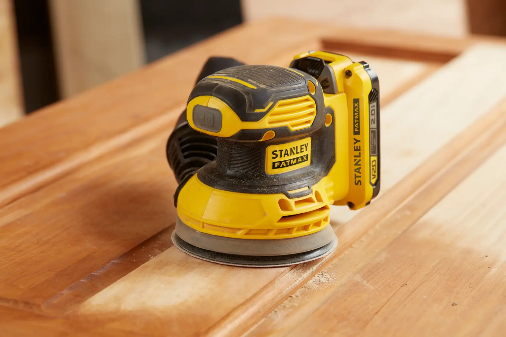 STANLEY SFMCW220D1S levigatrice orbitale senza fili giallo e nera, leviga una superficie di legno.
