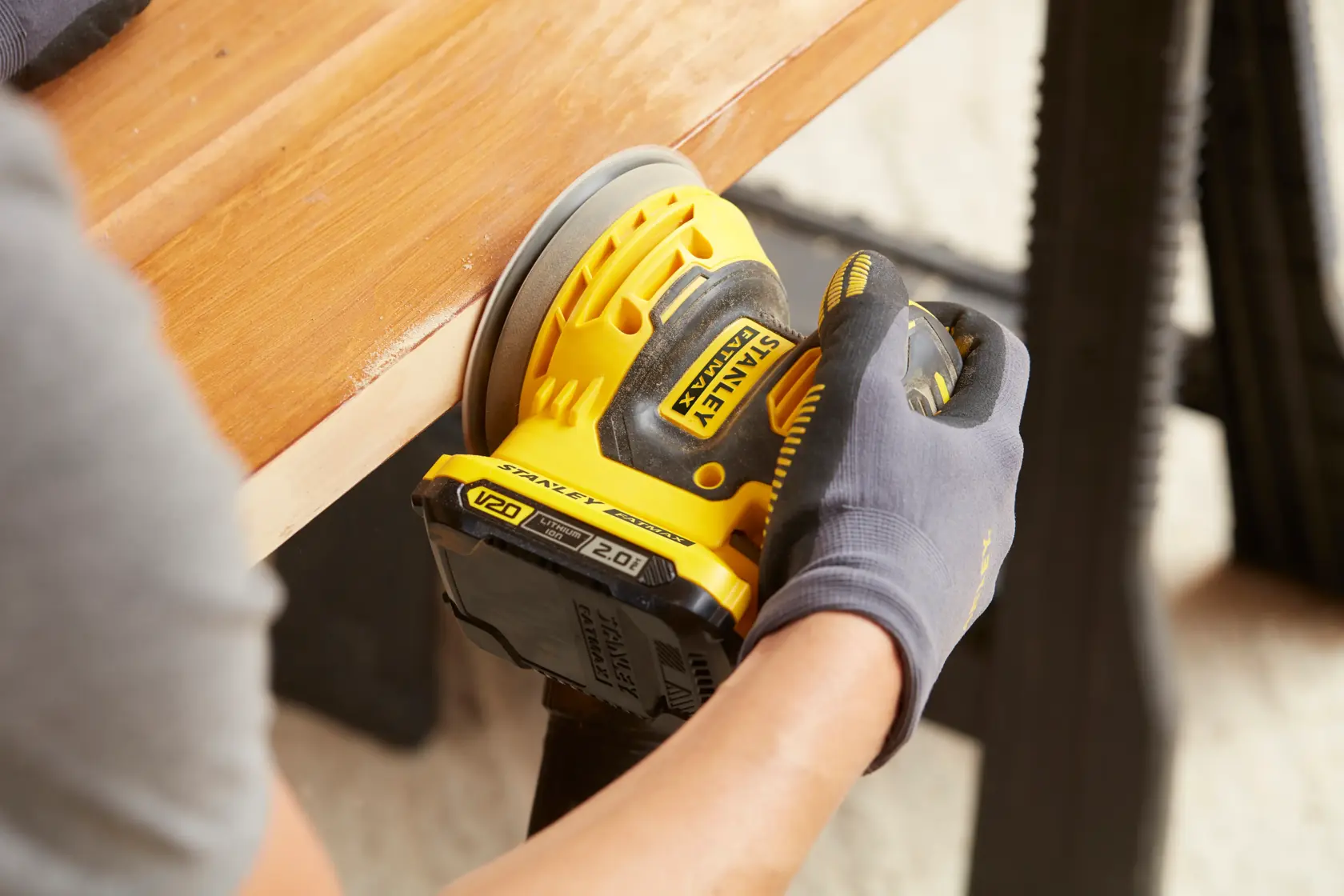 Foto della levigatrice cordless STANLEY SFMCW220D1S in uso su una superficie di legno.
