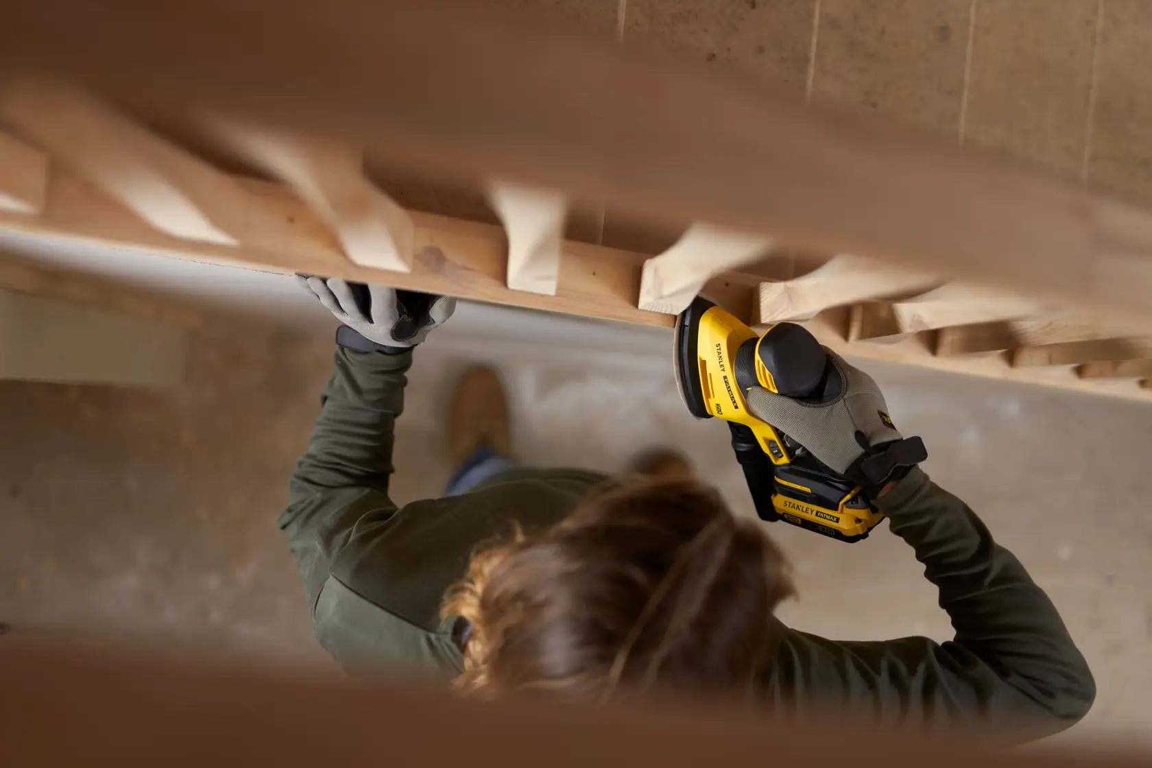 STANLEY SFMCW221D1S levigatrice senza fili usata su scale in legno, vista dall'alto.