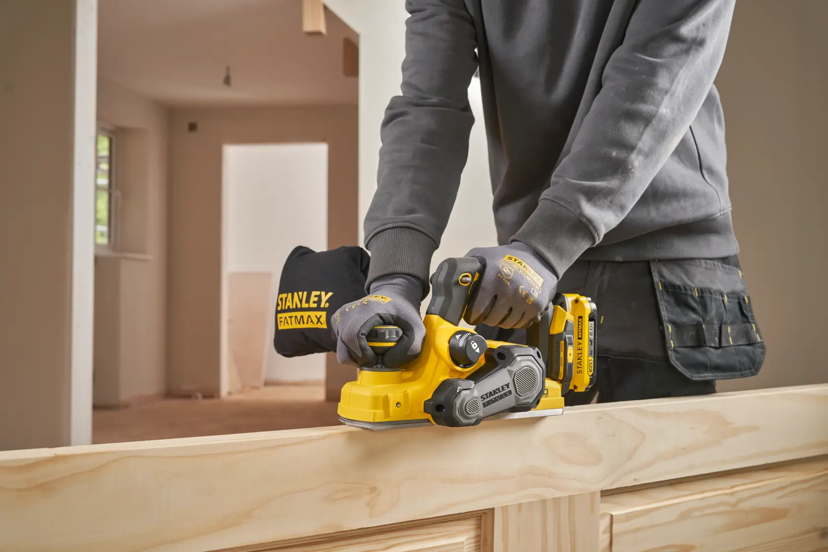 Pialletto a batteria STANLEY SFMCW300B in uso su legno, operatore con guanti, ambientazione interna.