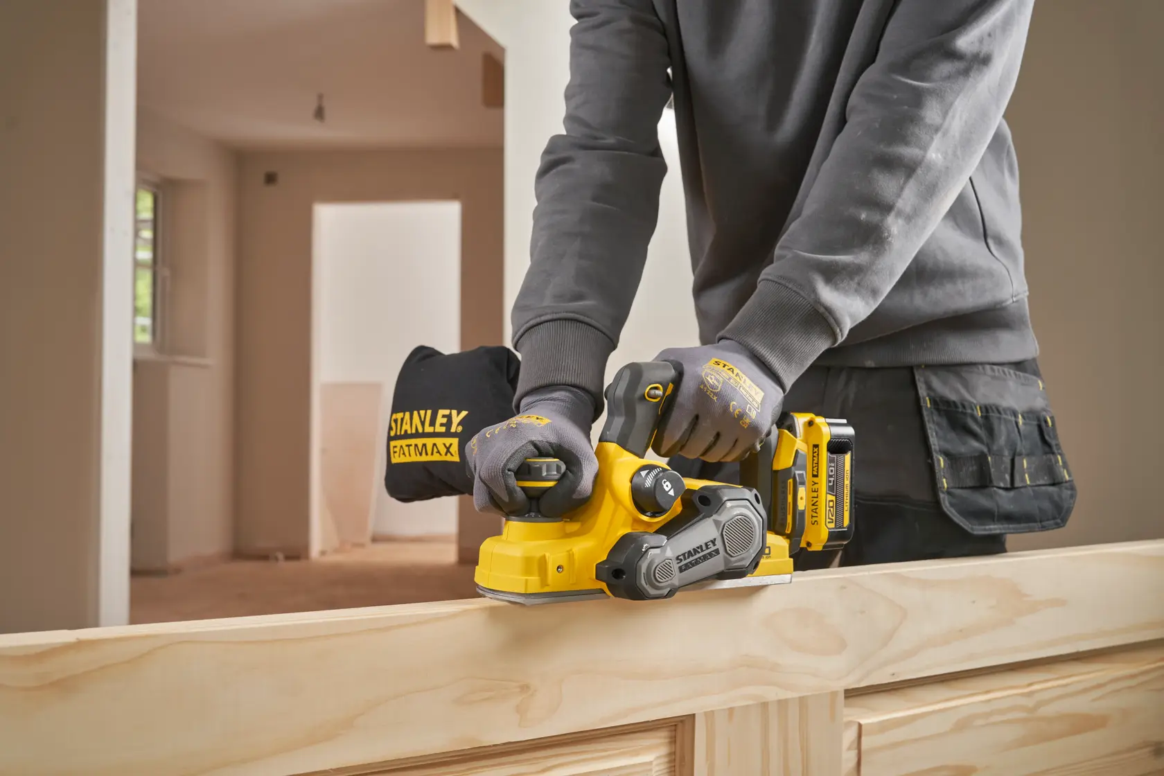 Stanley SFMCW300B rabot sans fil utilisé sur du bois, angle latéral, opérateur avec des gants.