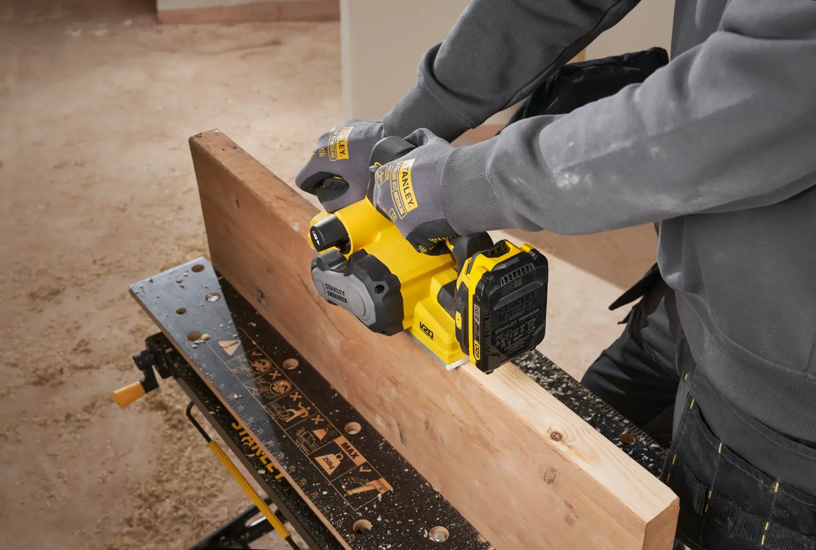 Piallatrice senza fili STANLEY SFMCW300B in uso su trave di legno, vista laterale, utente con guanti.