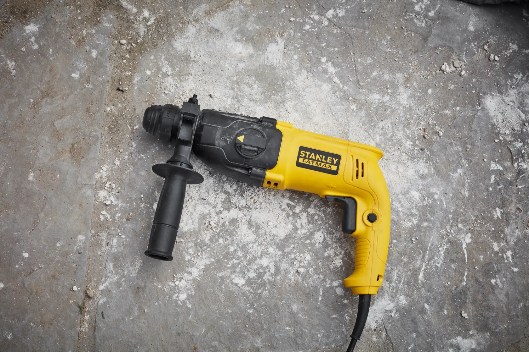 STANLEY SFMEH200K yellow and black corded hammer drill with side handle on concrete.