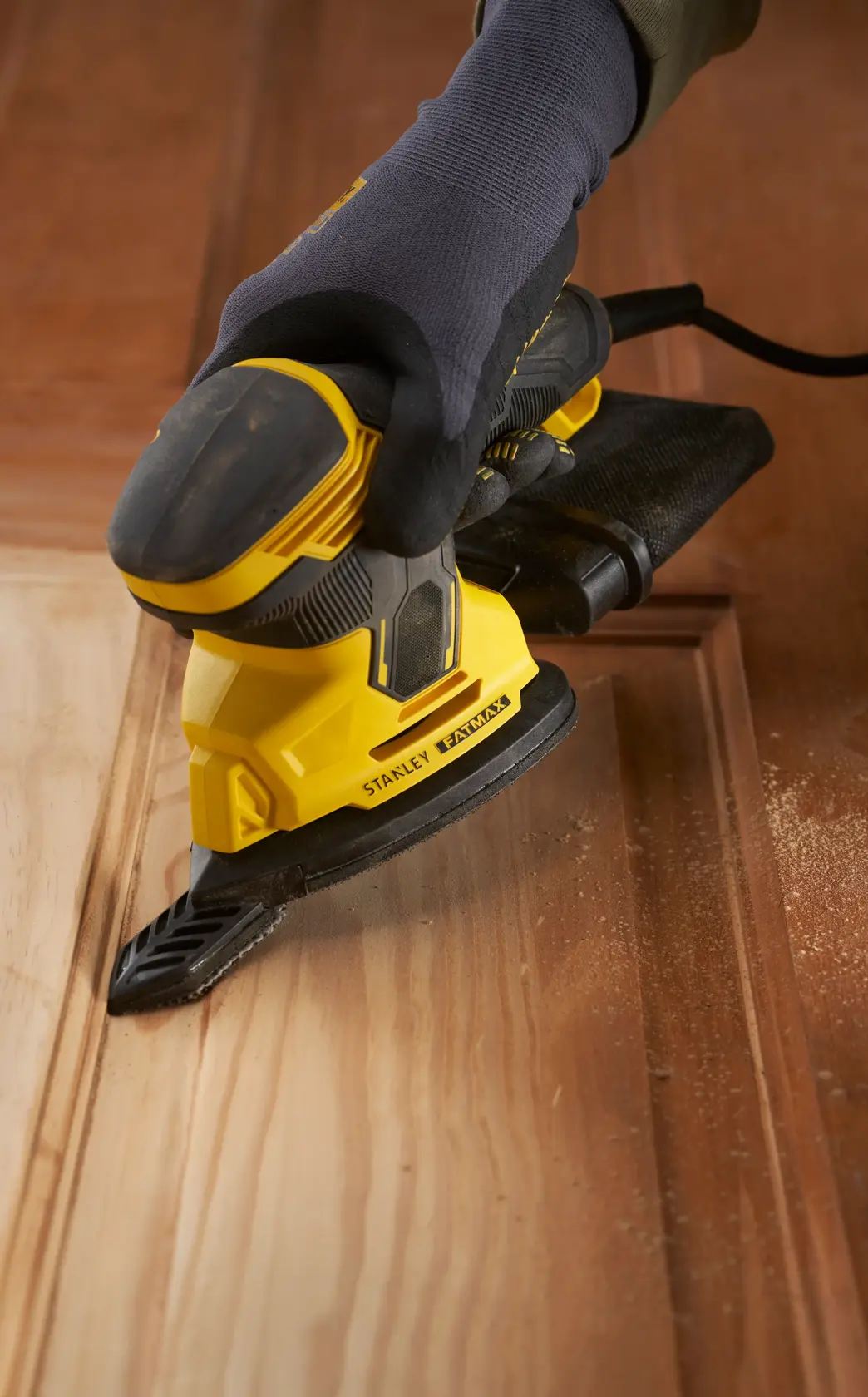 Stanley SFMEW210S levigatrice, gialla e nera, usata su legno, primo piano angolato.