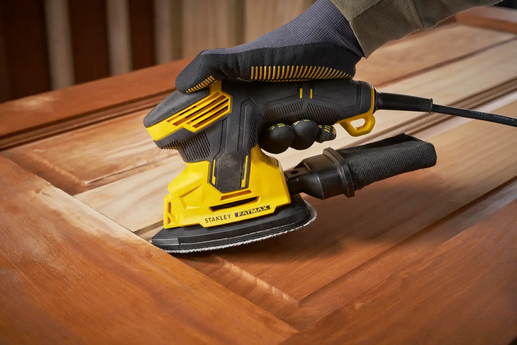 Stanley SFMEW210S levigatrice su superficie in legno, primo piano, design giallo e nero, fotografia utensile elettrico.