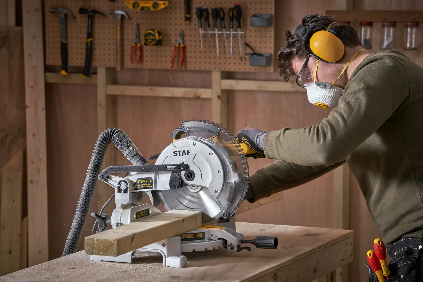 Foto della troncatrice STANLEY SM1650 che taglia legno in officina con una persona che indossa dispositivi di protezione.