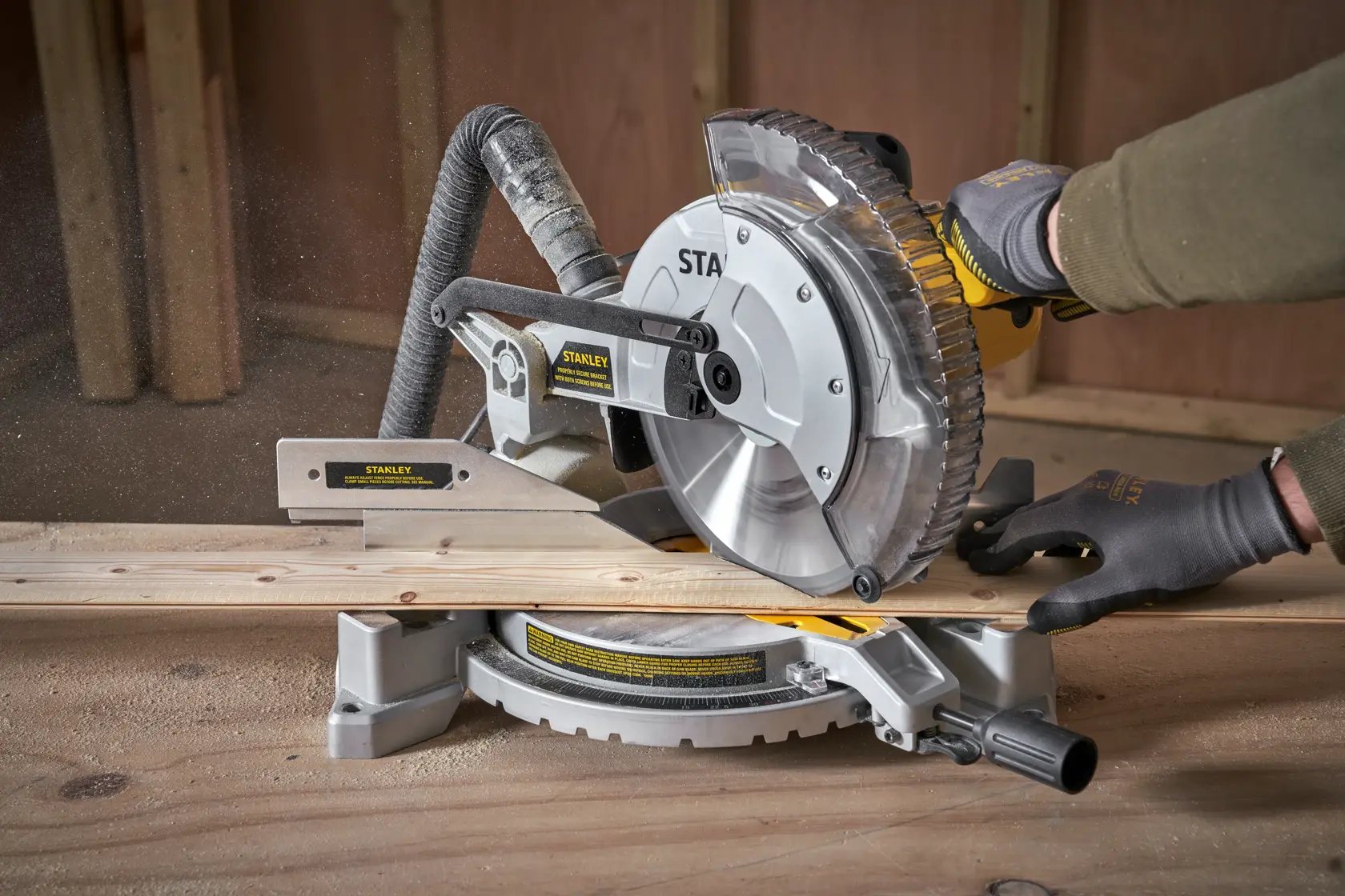 Troncatrice STANLEY SM1650 taglia legno, primo piano laterale, operatore con guanti in laboratorio.