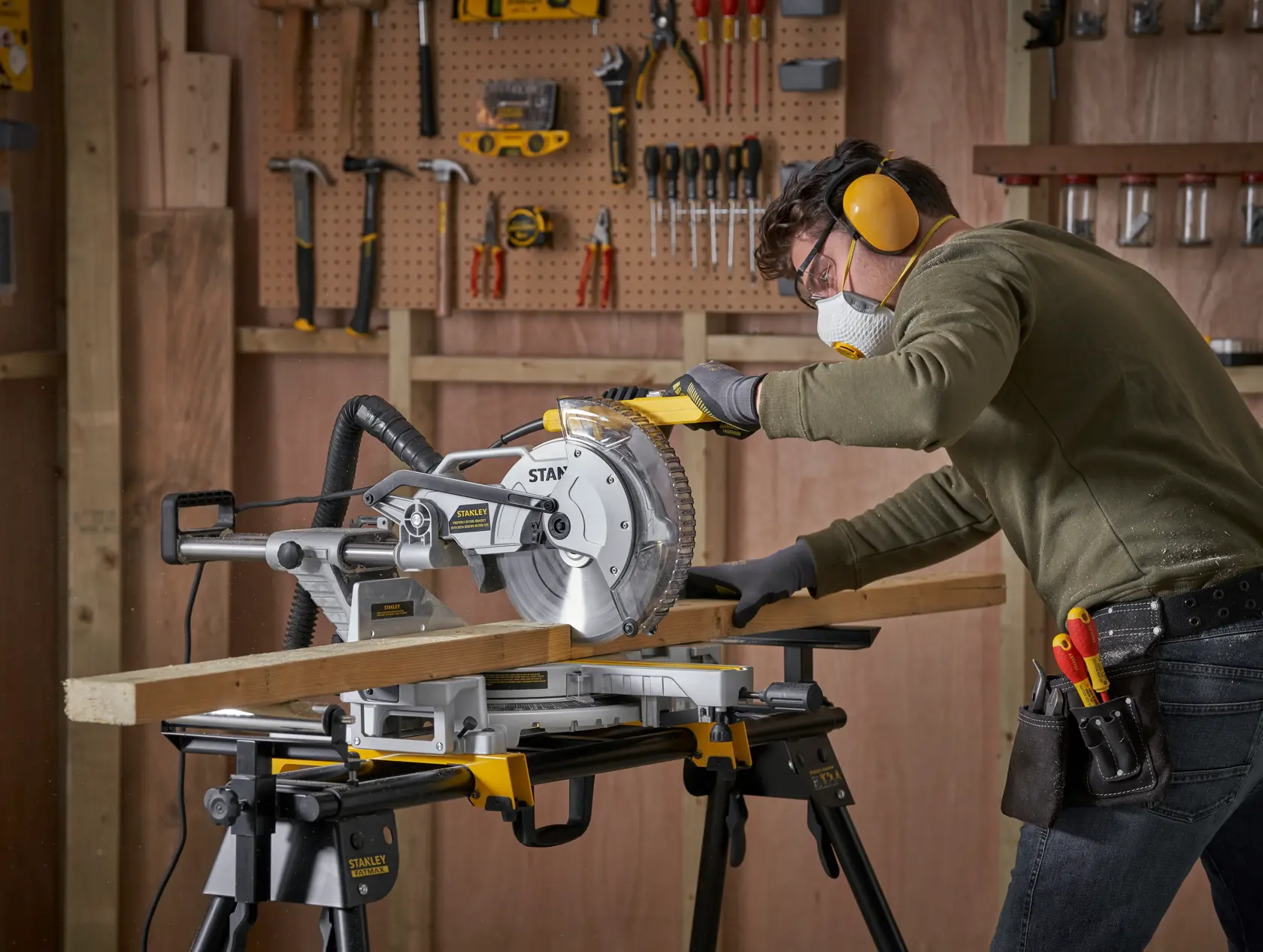 Troncatrice STANLEY SM1800 in uso, taglio di legno in officina con attrezzi sulla parete, vista laterale.