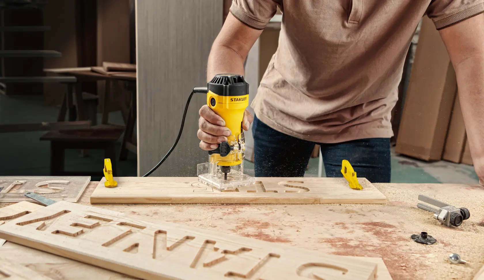 Défonceuse STANLEY ST55-B2 utilisée pour graver des lettres sur du bois dans un atelier.