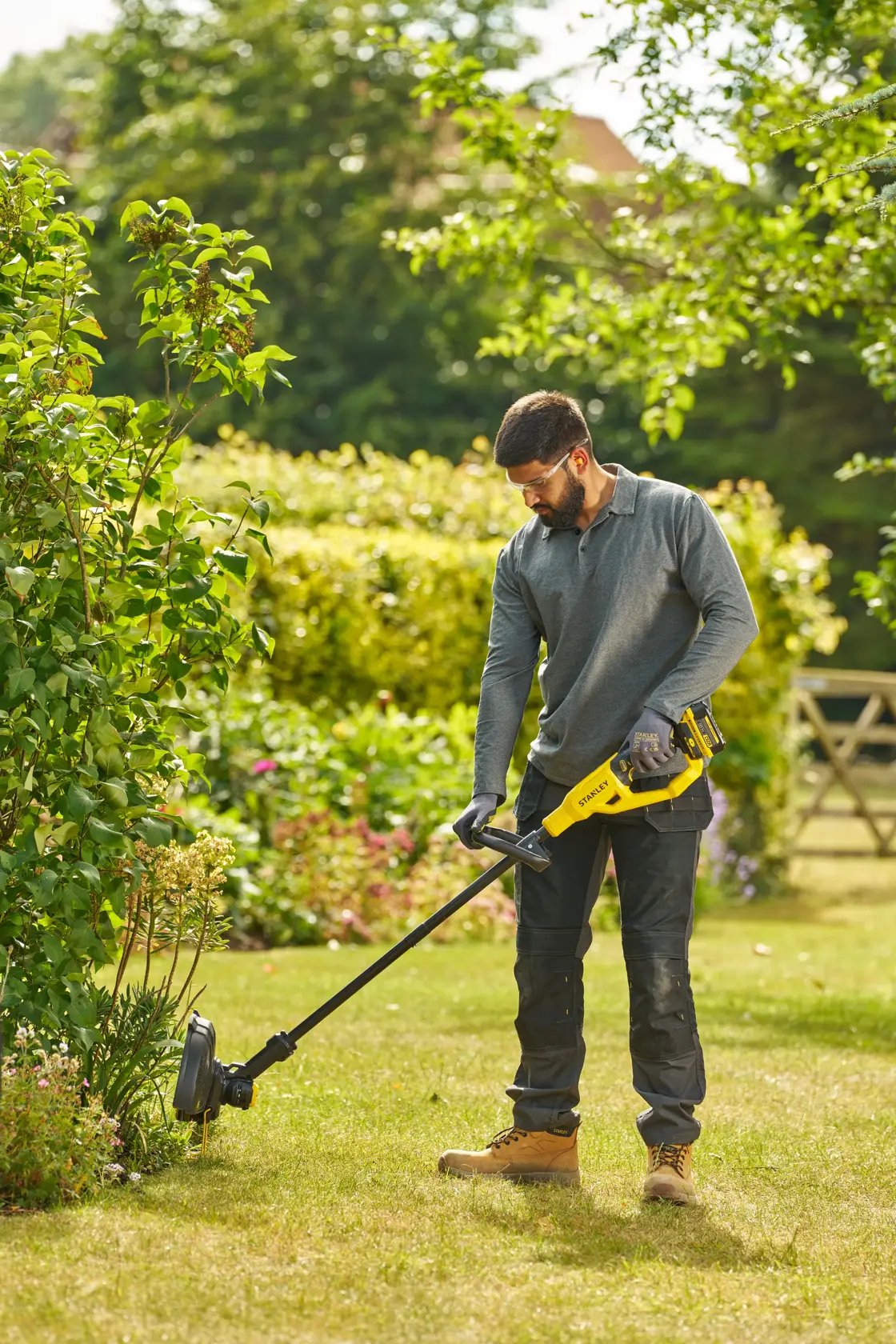 STANLEY STCST933M1 coupe-bordures utilisé en extérieur par une personne, design jaune et noir.