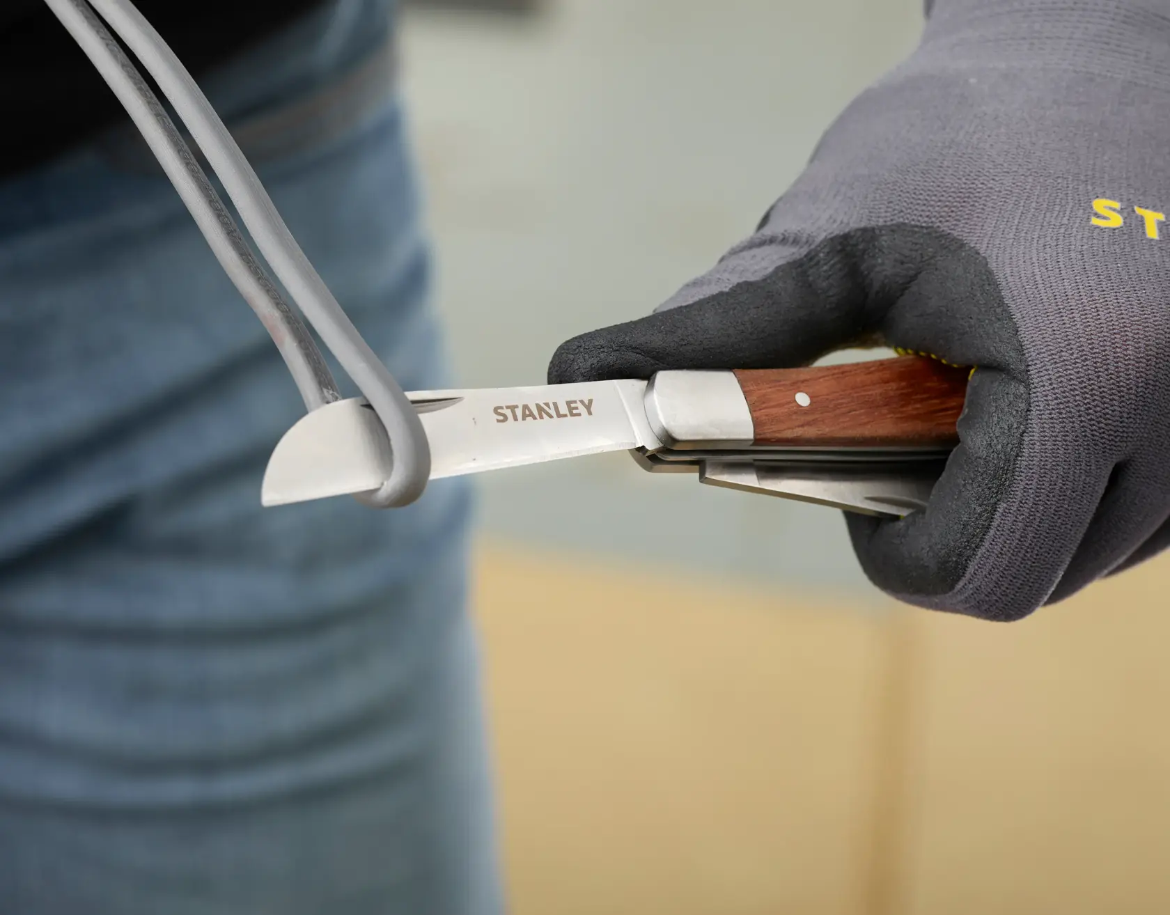 STANLEY STHT0-62687 pocket knife with wood handle cutting cable, close-up photography.