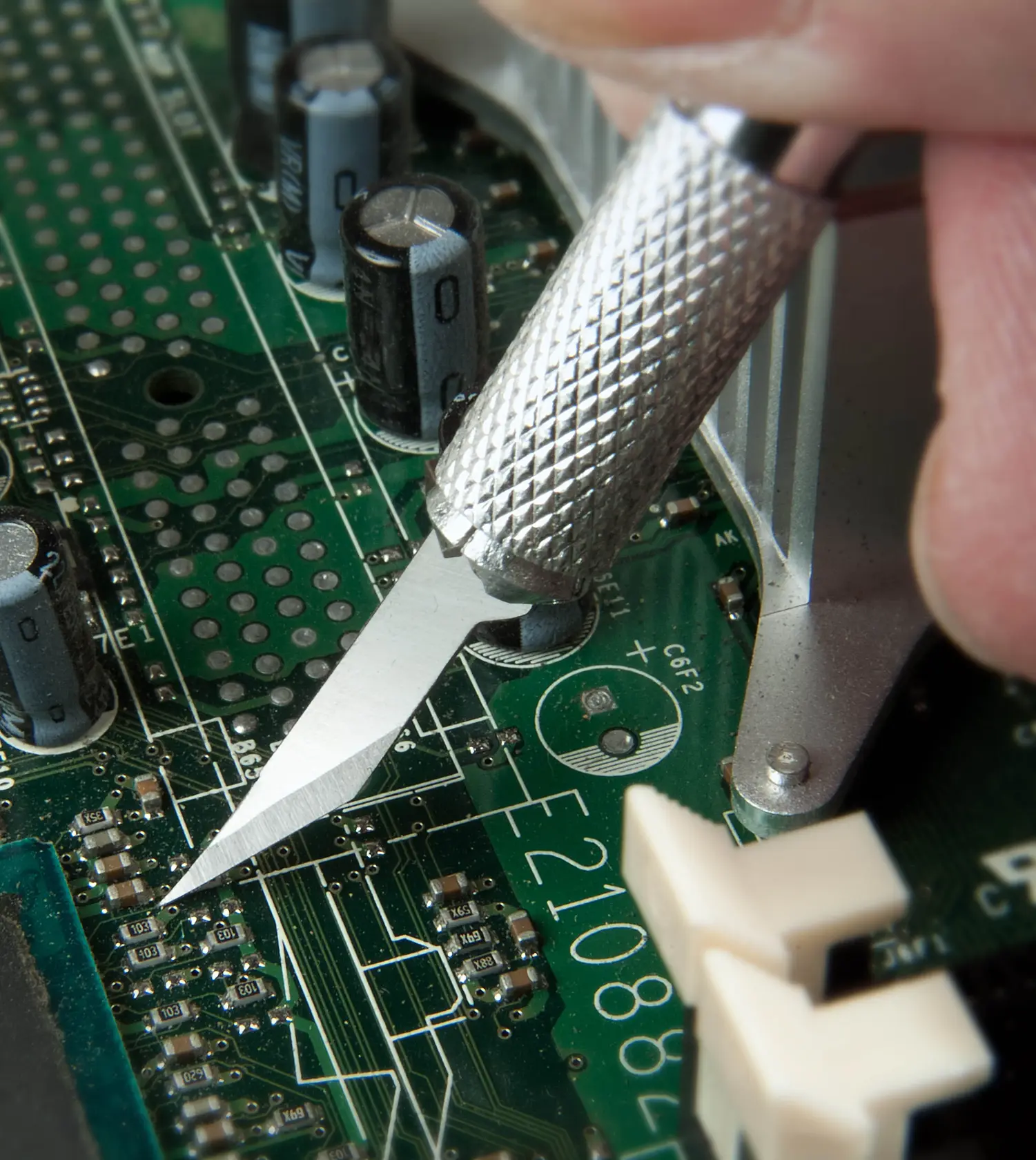STANLEY STHT0-73872 precision knife cutting on a green circuit board, close-up photo.
