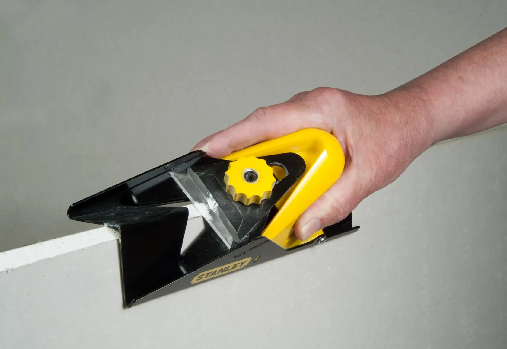 Photo of STANLEY STHT1-05937 hand-held plasterboard rasp in use on drywall edge.