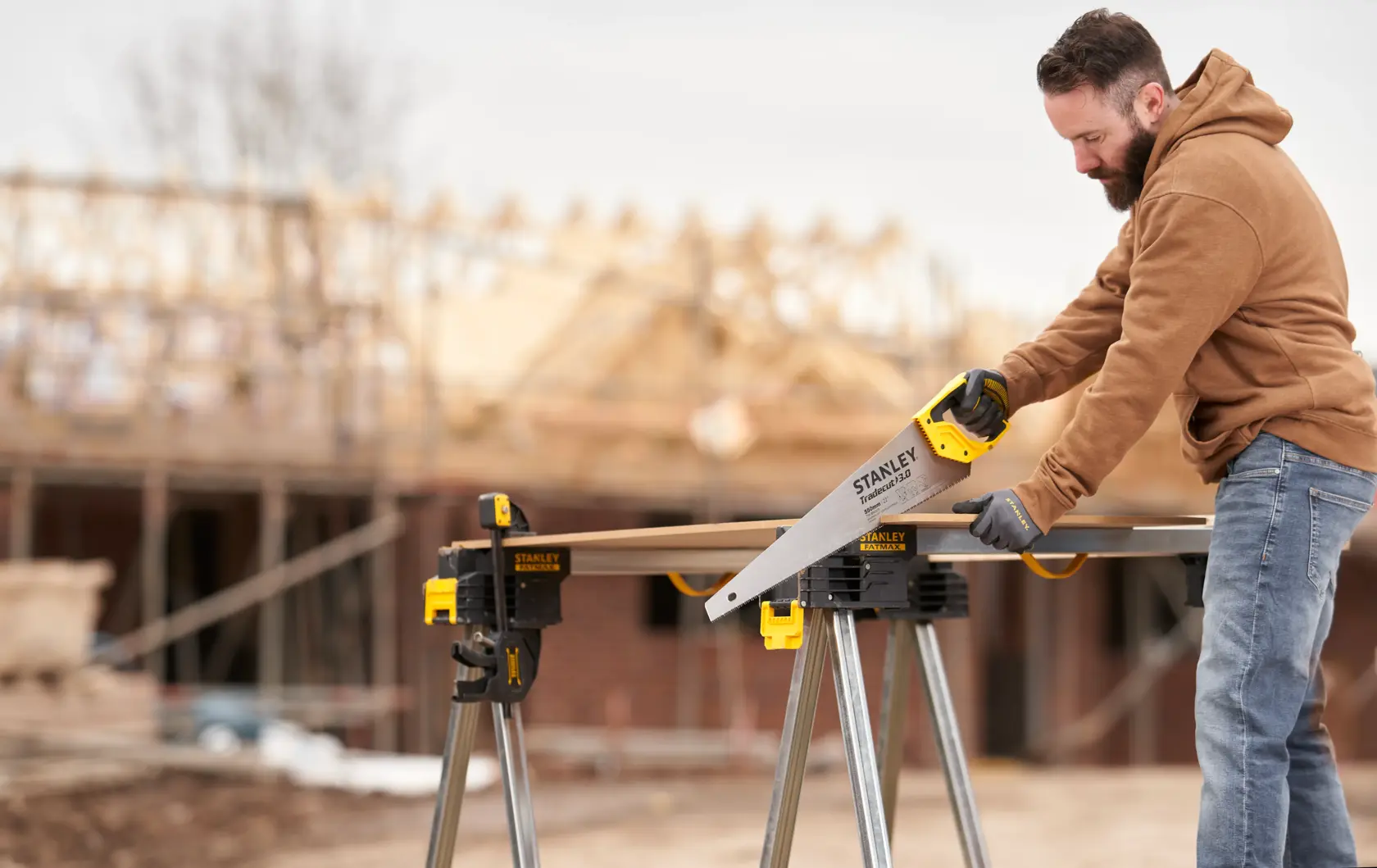 STANLEY STHT1-20352 scie à main utilisée à l’extérieur sur un chantier, coupe du bois sur un établi.