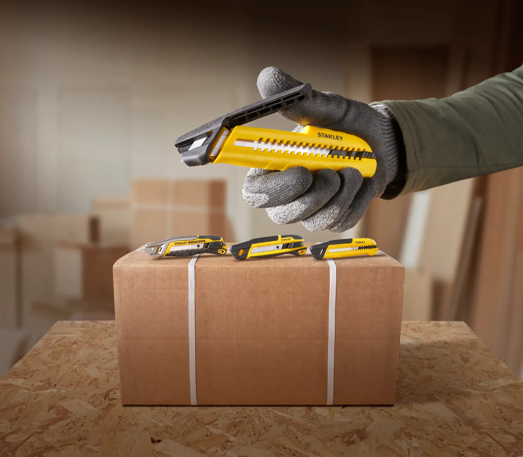 Foto des gelb-schwarzen STANLEY STHT10489 Cuttermessers neben einem Karton in einer Werkstatt.