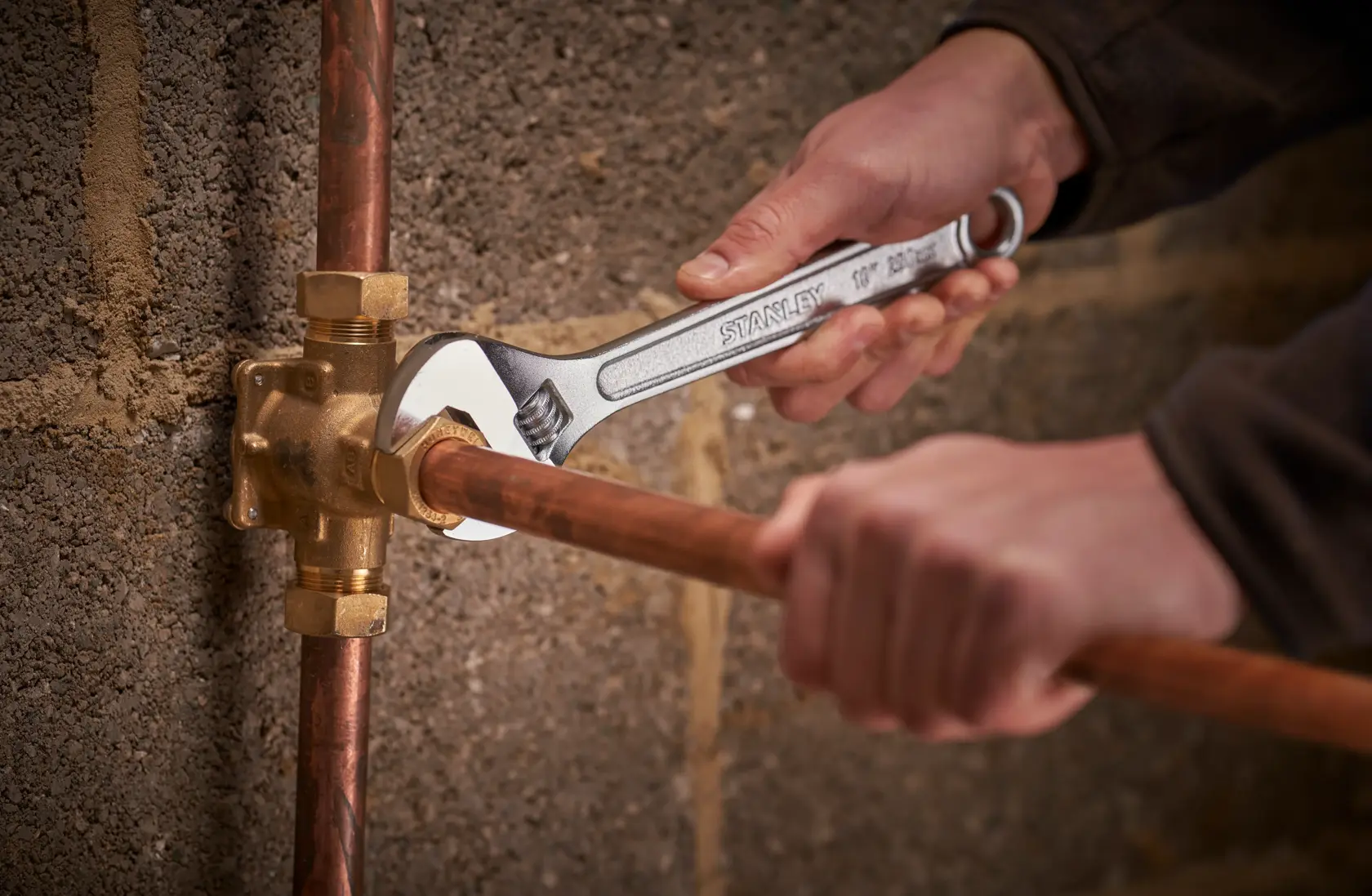 Stanley STHT13121-0 adjustable wrench used on copper plumbing pipe, close-up photography.