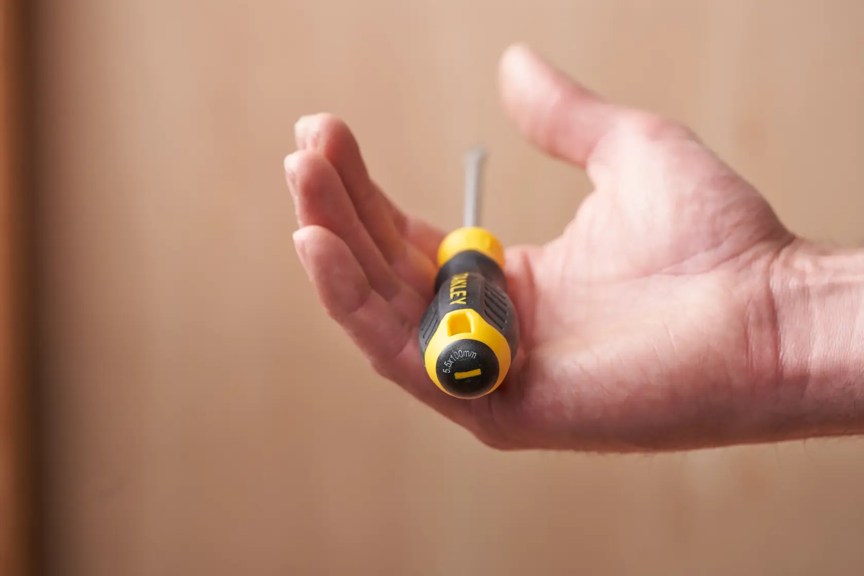 STANLEY STHT16146-0 screwdriver held in hand, yellow and black grip, close-up photo.