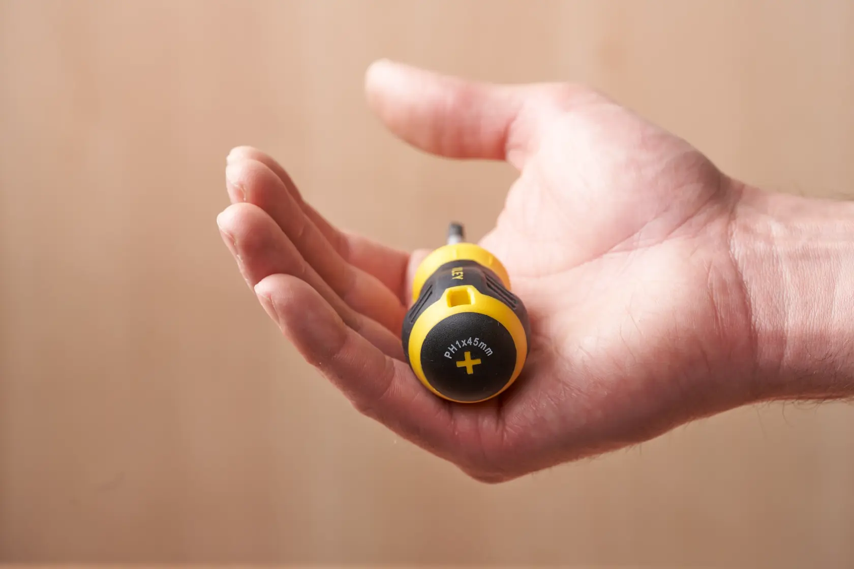 STANLEY STHT16154-0 screwdriver in a hand, yellow and black handle, photography close-up.