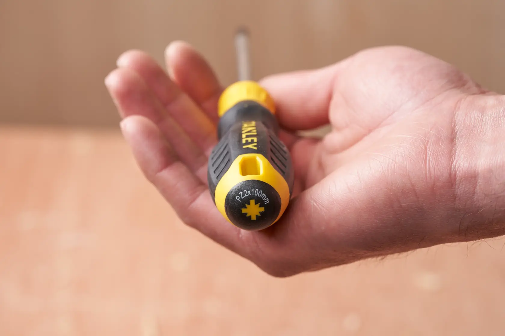 Photo of STANLEY STHT16163-0 screwdriver with black and yellow handle in a hand, end cap with size marking.