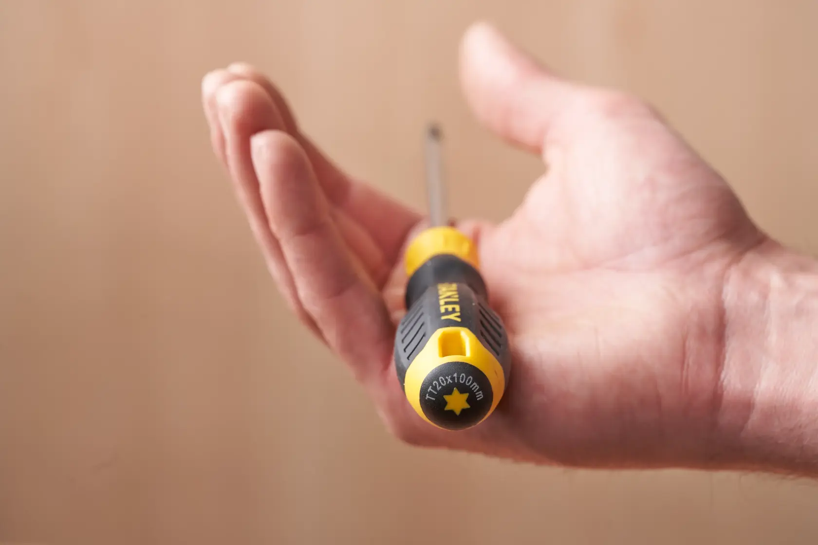 Photo of STANLEY STHT16179-0 screwdriver with black and yellow handle resting in an open hand.