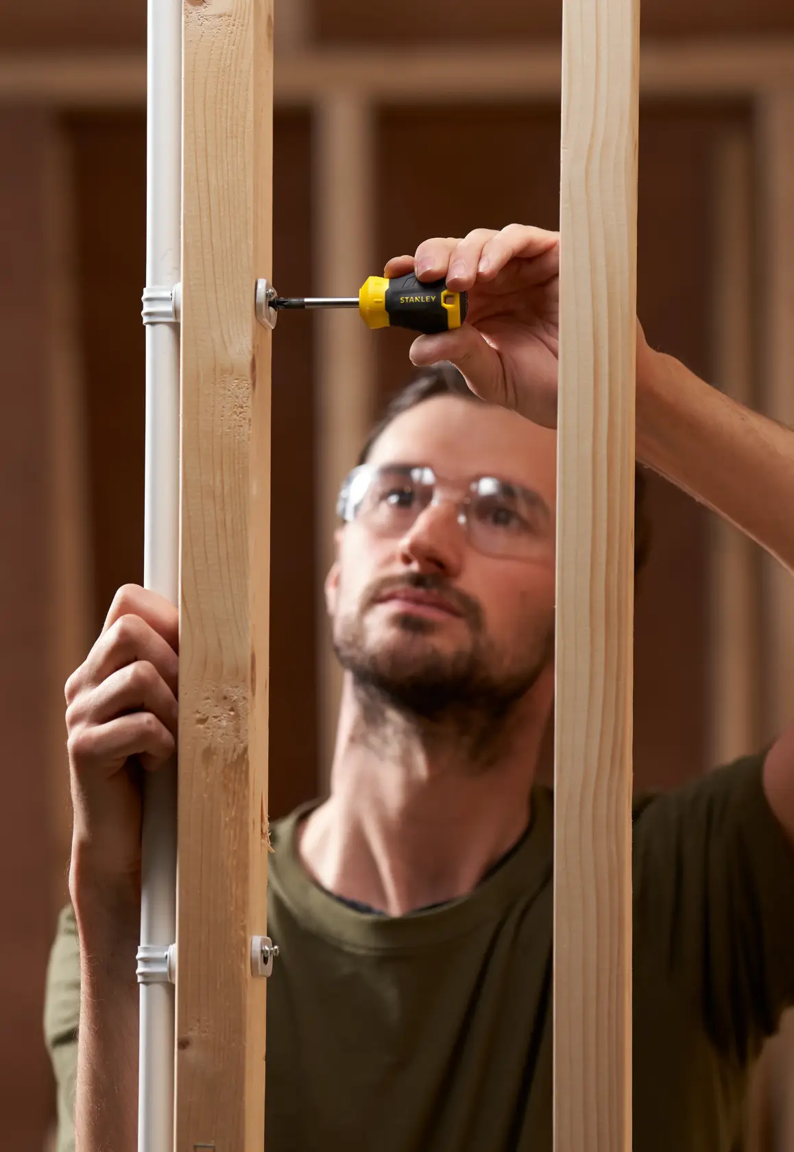Photo of STANLEY STHT16196-0 screwdriver used on wooden framing, close-up during construction.