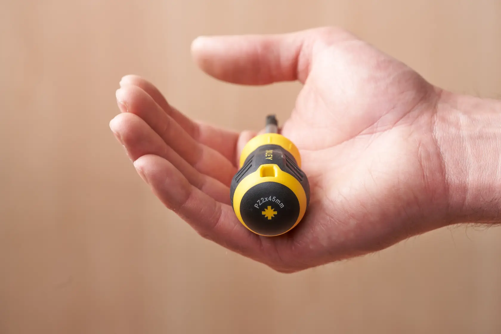 STANLEY STHT16196-0 yellow and black stubby screwdriver held in an open hand, side view.