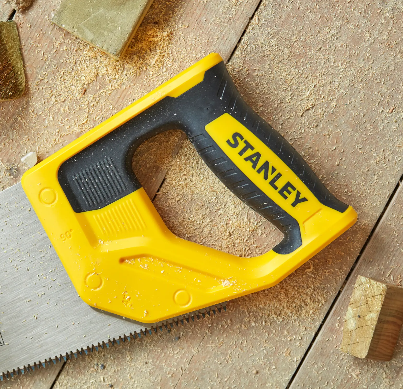 STANLEY STHT20351-1 scie à main avec poignée jaune et noire, gros plan sur bois et sciure.