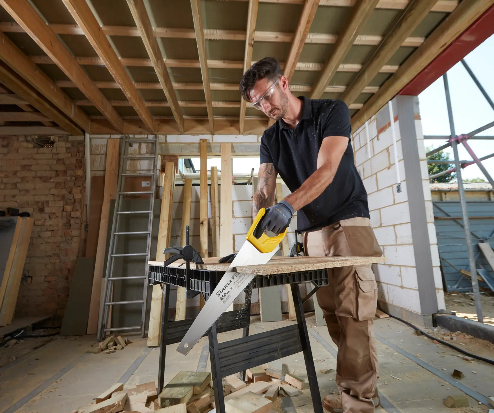 STANLEY STHT20354-1 scie à main avec manche jaune utilisée pour couper du bois sur un chantier.
