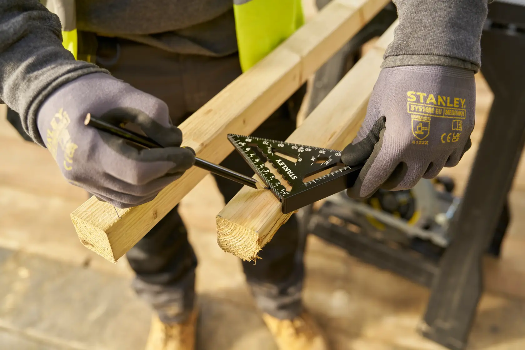 Squadra da carpentiere STANLEY STHT46100-0 utilizzata per misurare e segnare una trave in legno, lavoratore con guanti.