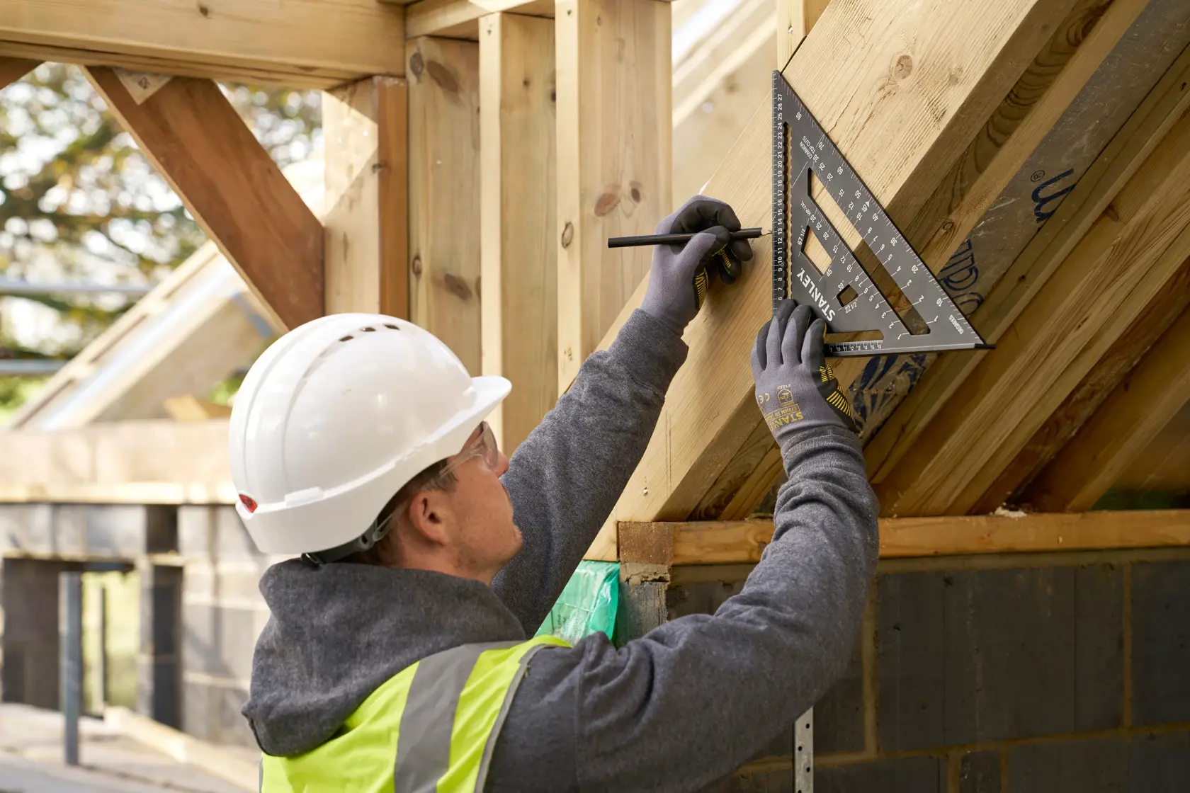 Squadra STANLEY STHT46102-0 usata da operaio per segnare telaio in legno su cantiere.
