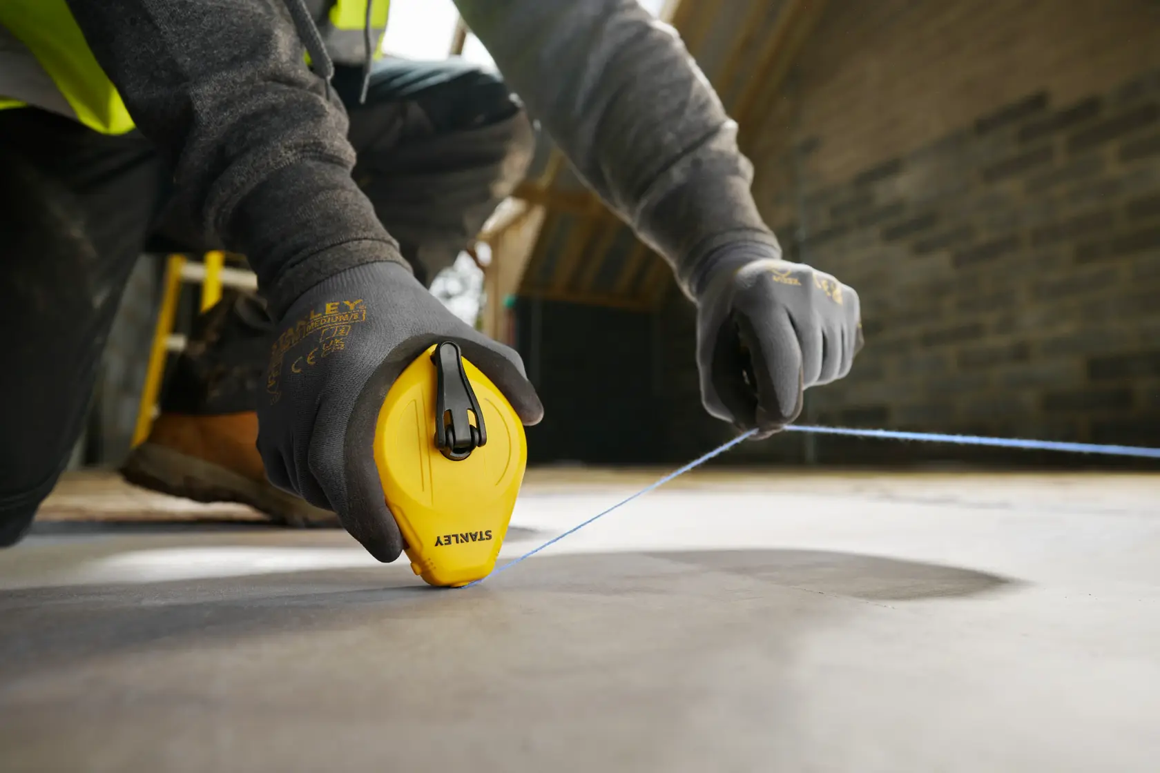 Foto dello strumento linea tracciante STANLEY STHT47112-0 in uso su pavimento di cantiere.
