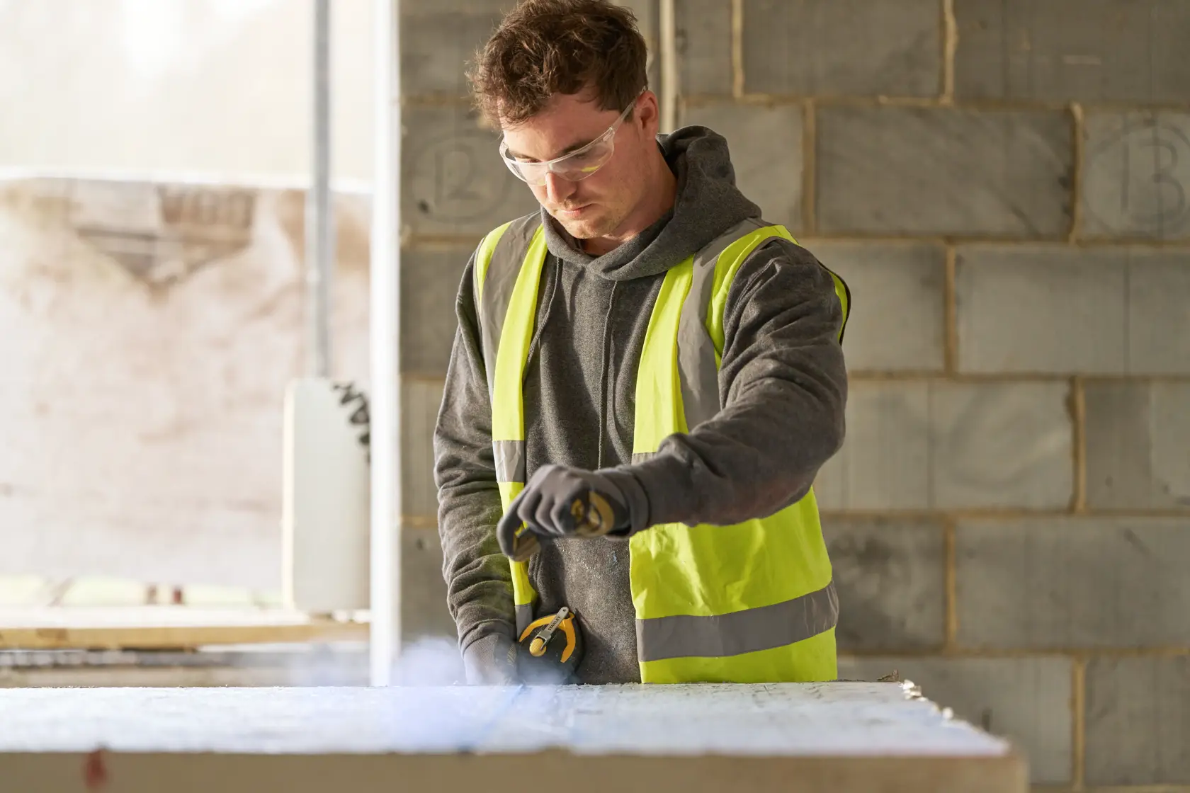 Fotografia di operaio STANLEY STHT47311-0 al lavoro con utensile in cantiere, indossa gilet ad alta visibilità.