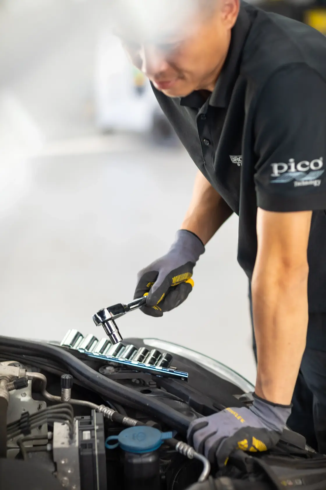 STANLEY STMT82670-0 socket wrench set used by mechanic with gloves while working on a car engine, front angle.