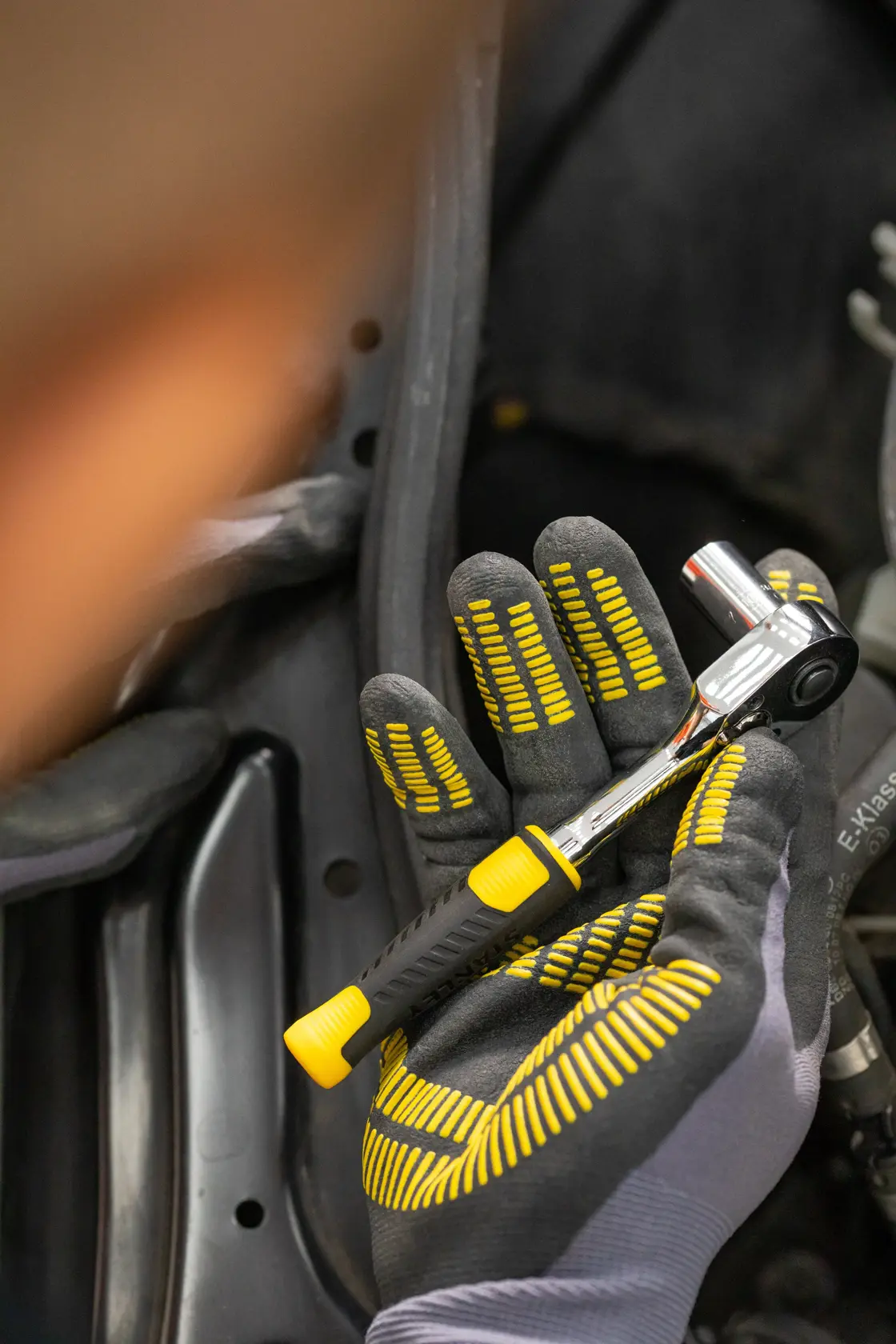 STANLEY STMT82828-1 ratchet wrench with black and yellow handle, held in gloved hand, close-up.