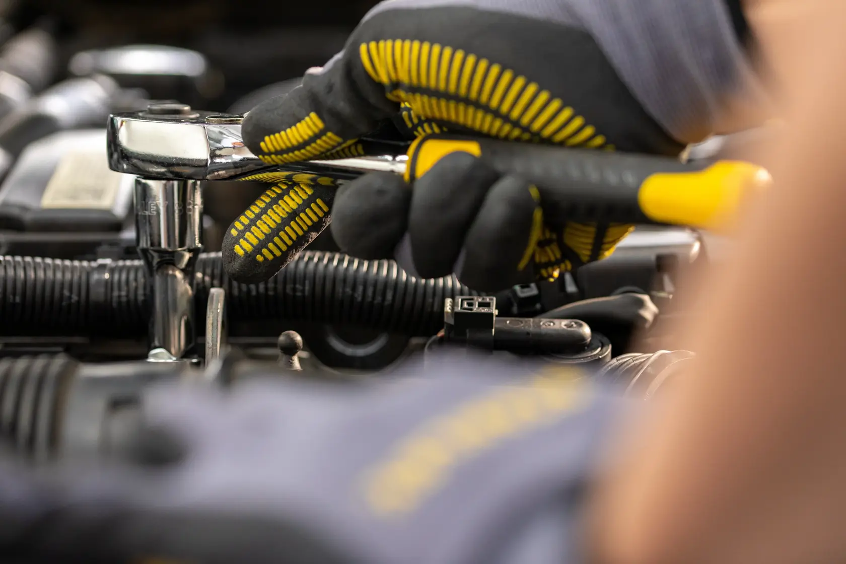 STANLEY STMT82830-1 ratchet wrench being used with gloves in automotive engine context, close-up photo.