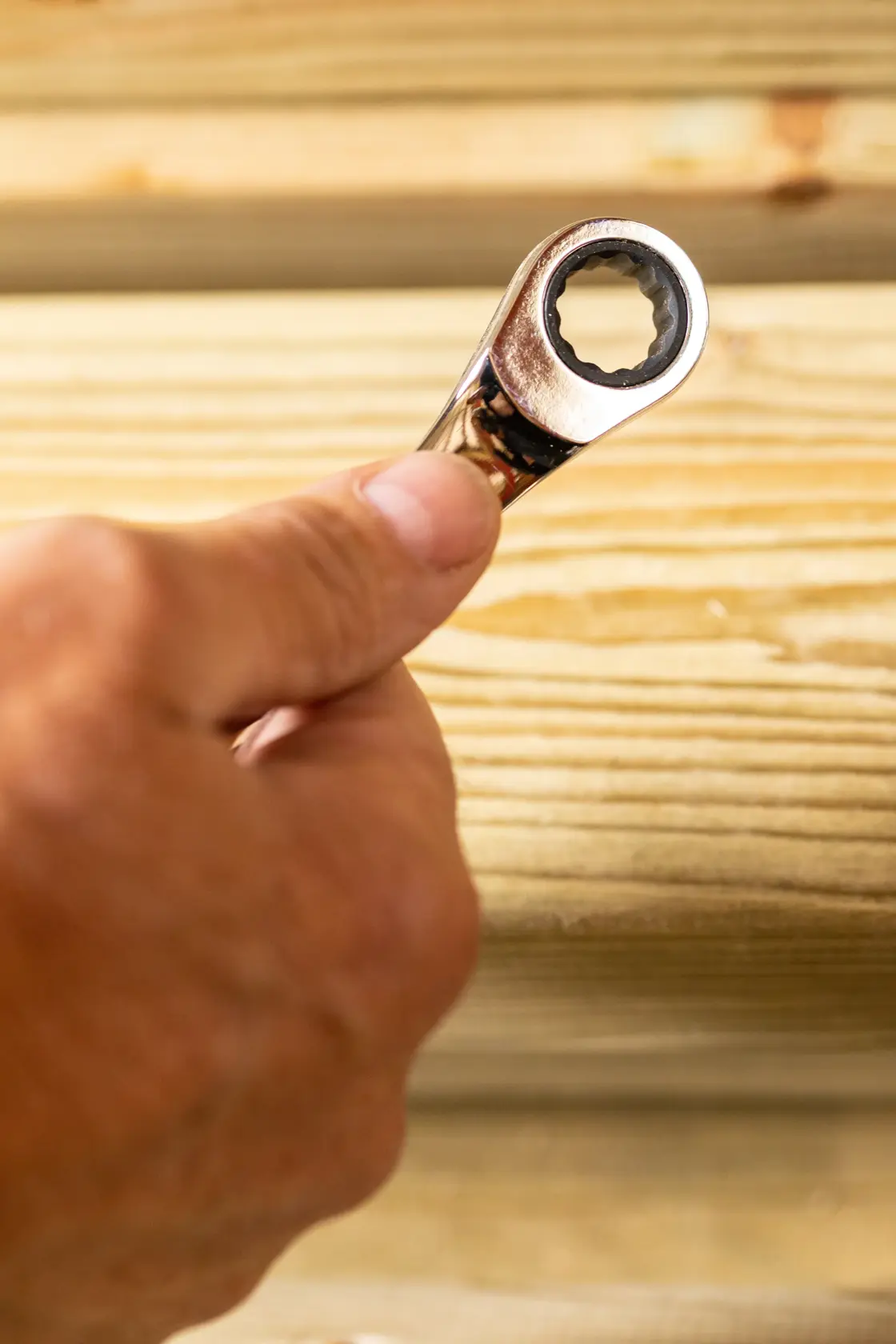 Photo of STANLEY STMT82846-0 ratcheting wrench held by hand against wood background.