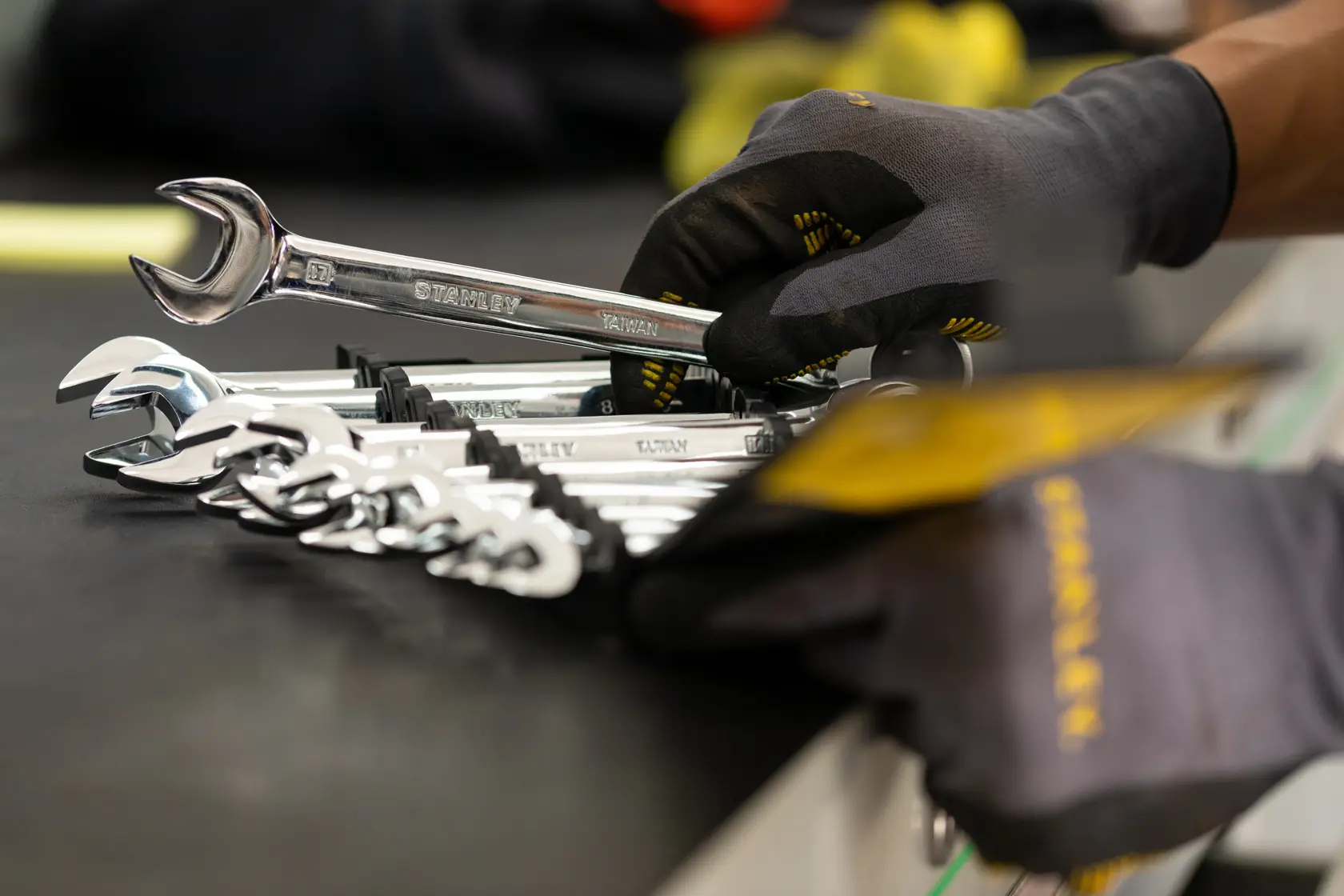 Photo of STANLEY STMT82847-0 wrench set with gloved hand picking a chrome wrench from a black holder.