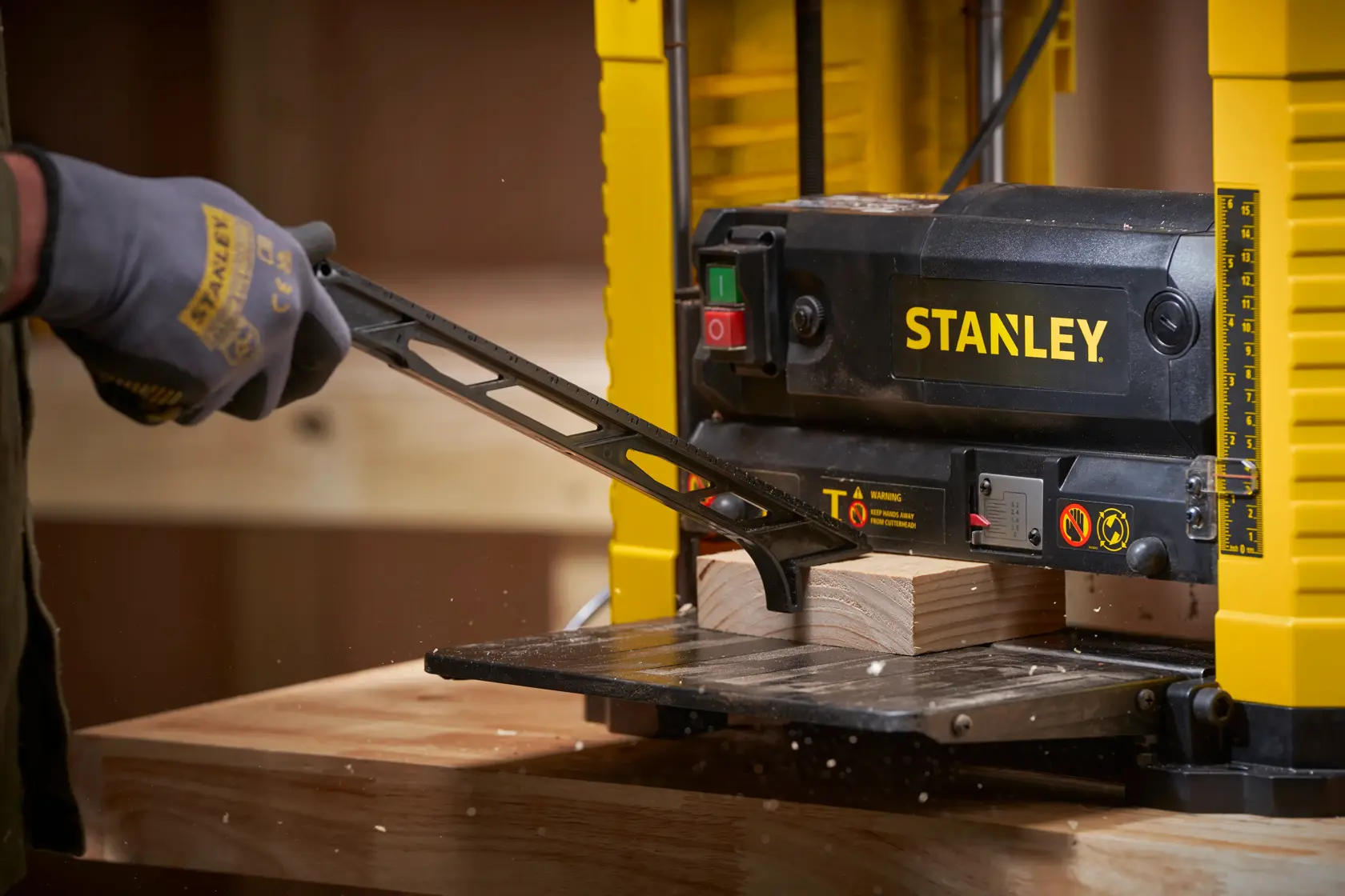 STANLEY STP18-B2 rabot de table en utilisation, vue rapprochée d'une main gantée ajustant une pièce de bois.