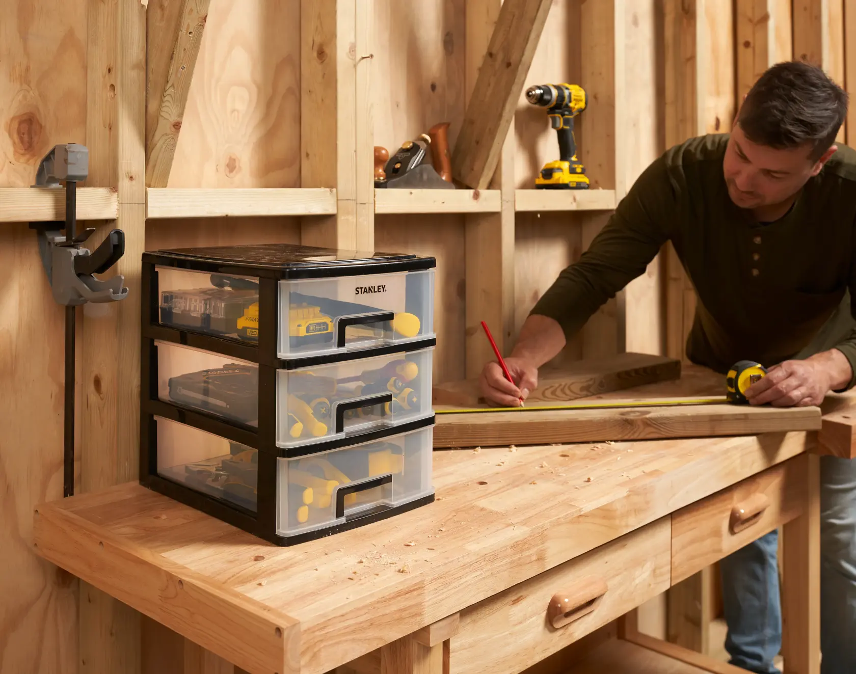 STANLEY STST40712-1 plastic drawer organizer on wooden workbench, filled with tools, in workshop setting.