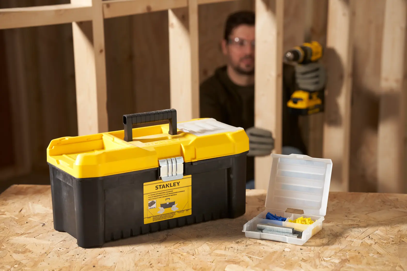 STANLEY STST75785-1 toolbox with yellow lid and black base, placed on a wooden workbench next to an open organizer.