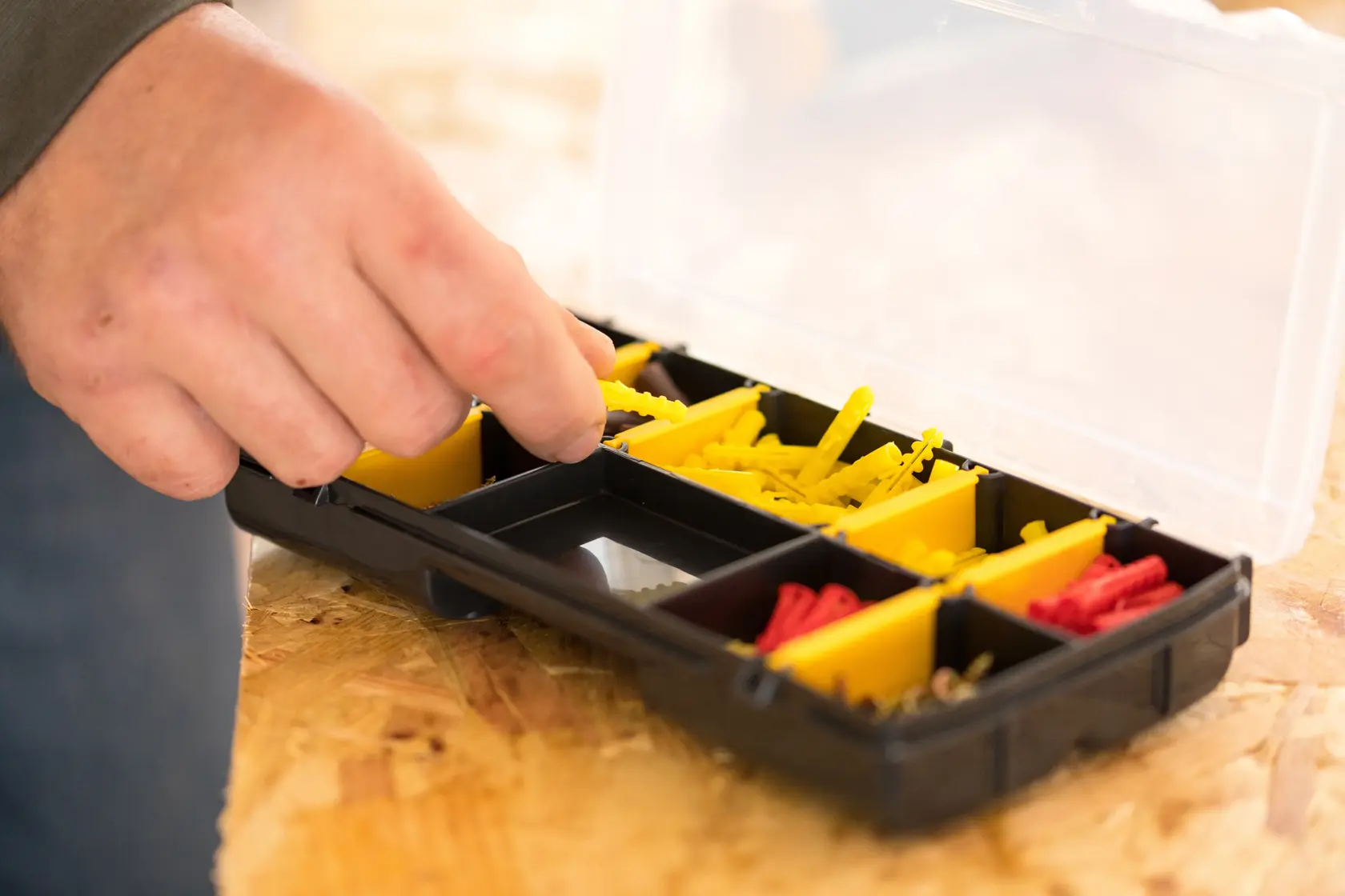 Boîte STANLEY STST81679-1 avec compartiments jaunes et rouges, main prenant un objet, vue de dessus.