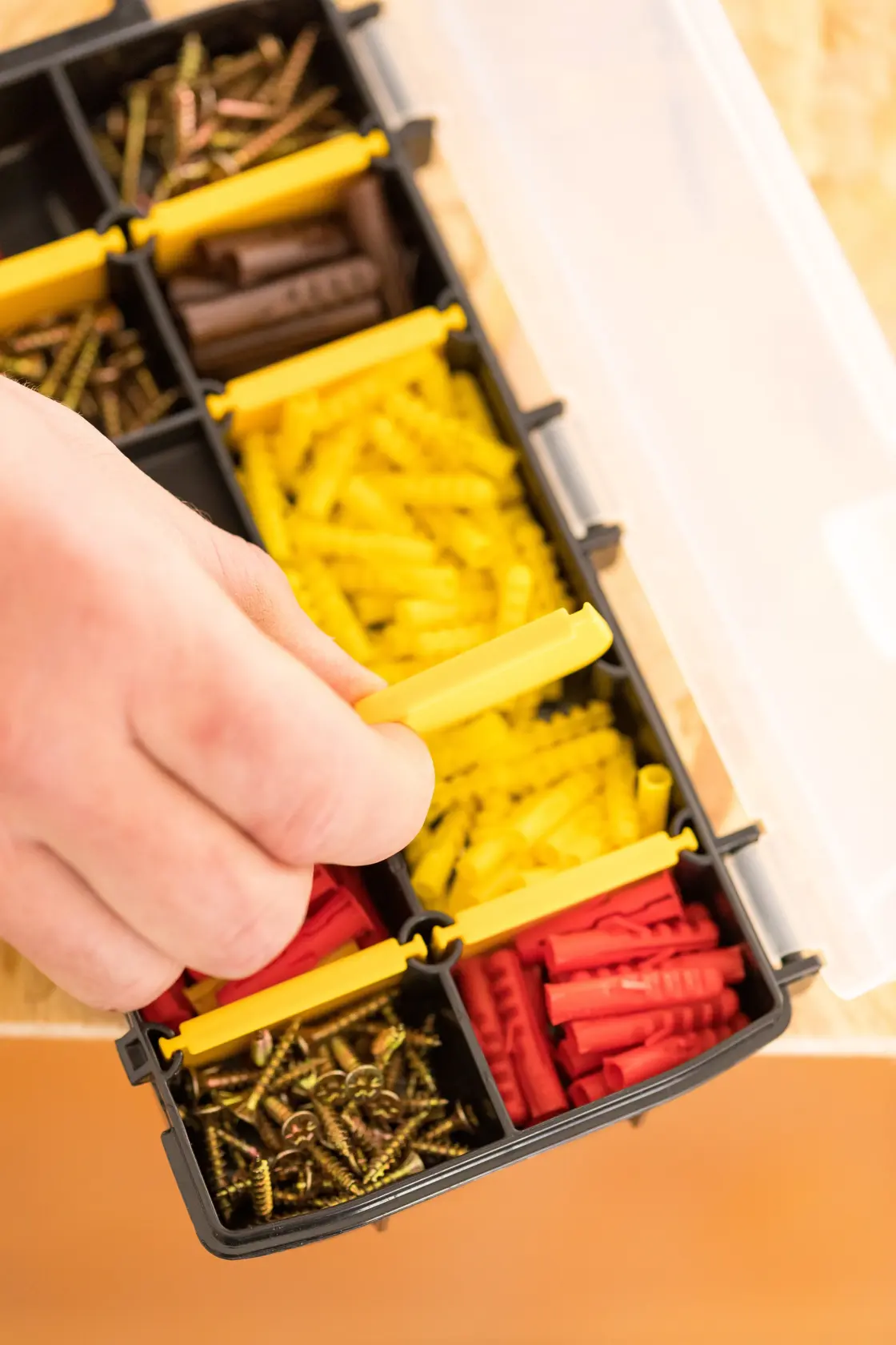 Organiseur STANLEY STST81679-1 avec vis et chevilles assorties, main ouvrant un compartiment, vue de dessus.