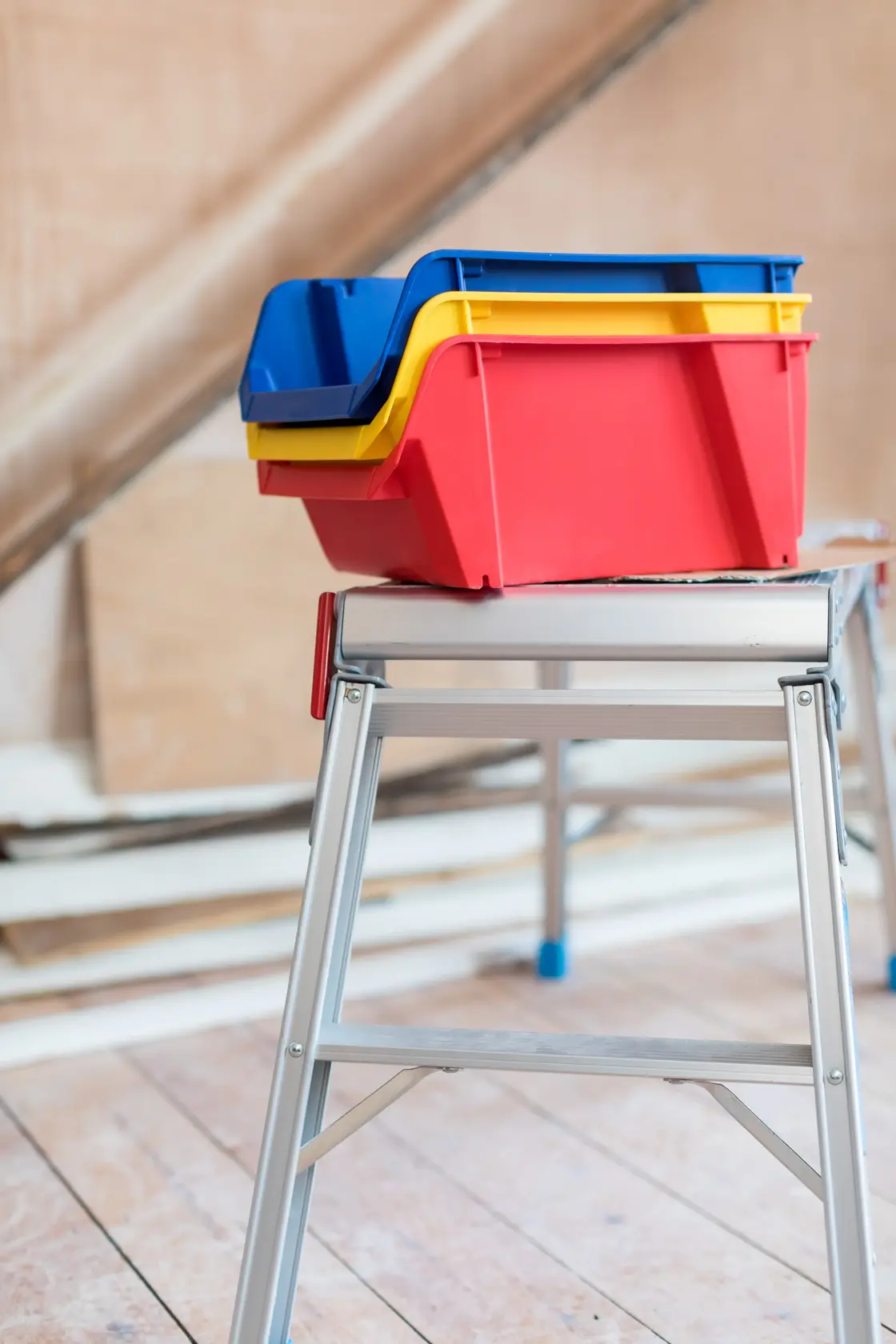 STANLEY STST82742-1 bacs de rangement empilables en plastique rouge, jaune et bleu sur établi en métal.