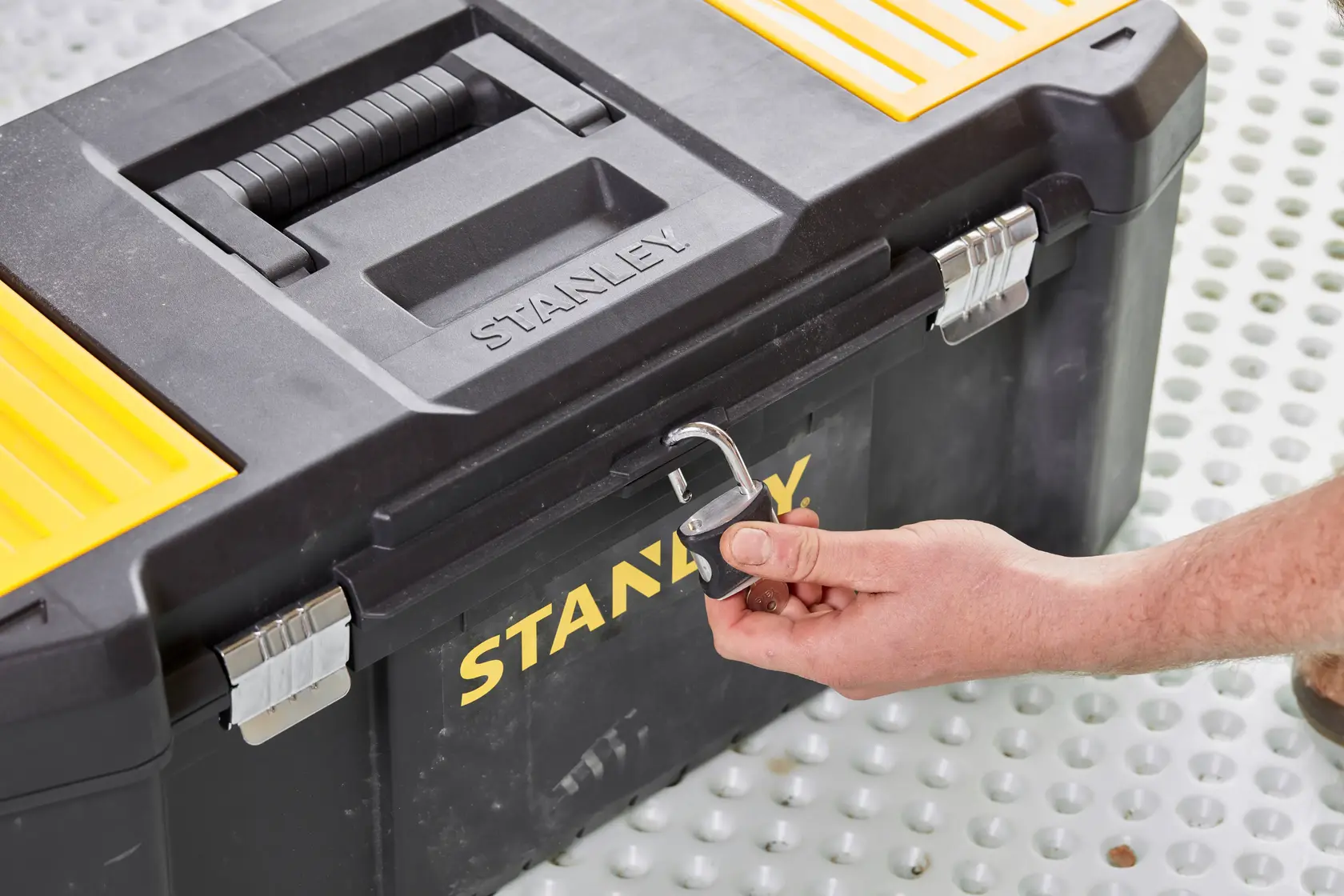 Photo of STANLEY STST82976-1 toolbox with padlock being unlocked, black and yellow plastic, close-up angle.