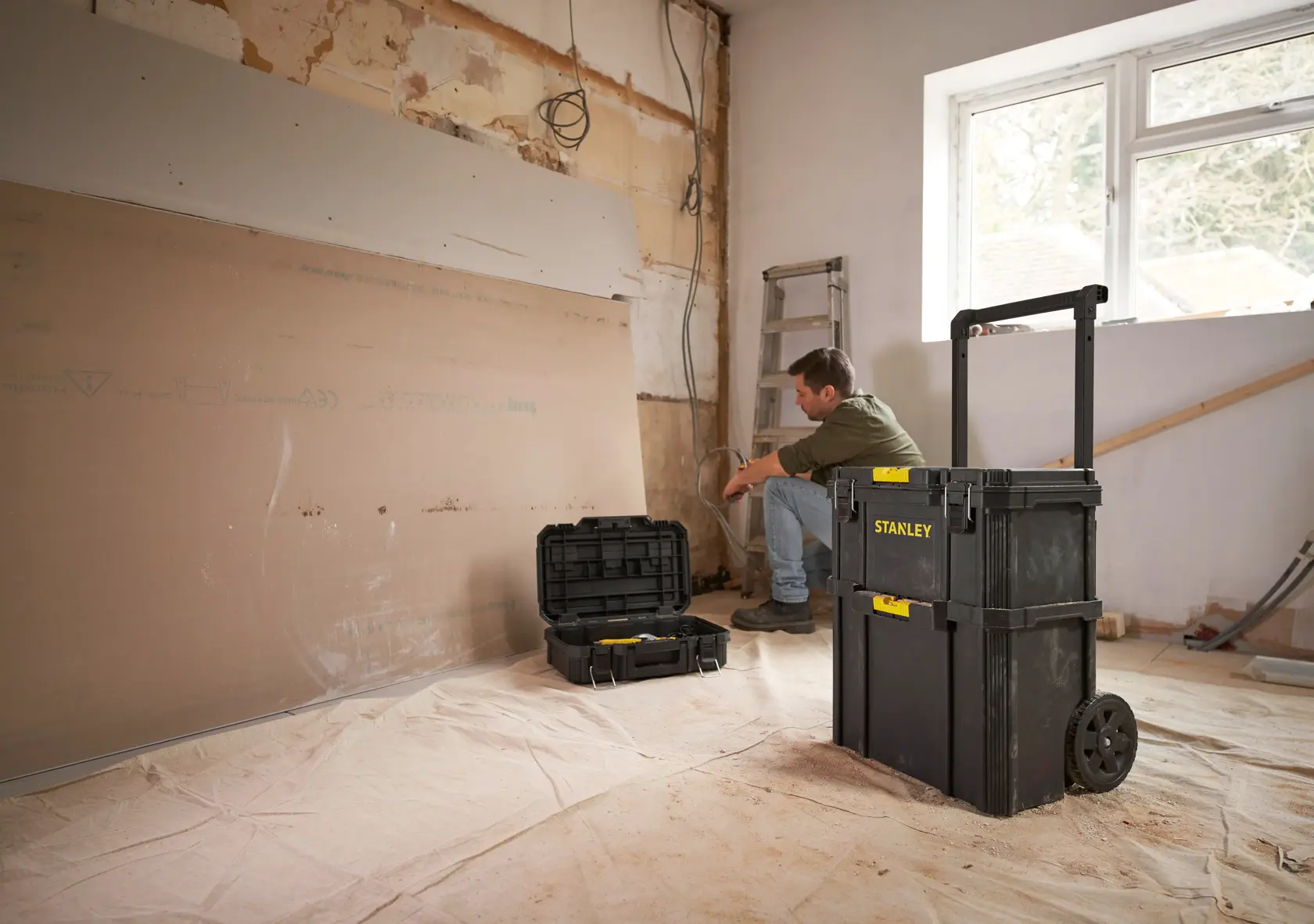 Stanley STST83319-1 rollende Werkzeugbox im Renovierungsumfeld mit offenem Koffer, Produktfoto in Nutzung.