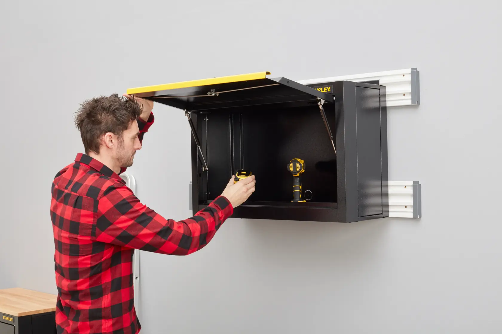 STANLEY STST97599-1 armoire murale noire avec couvercle jaune en utilisation, photographie angle latéral.